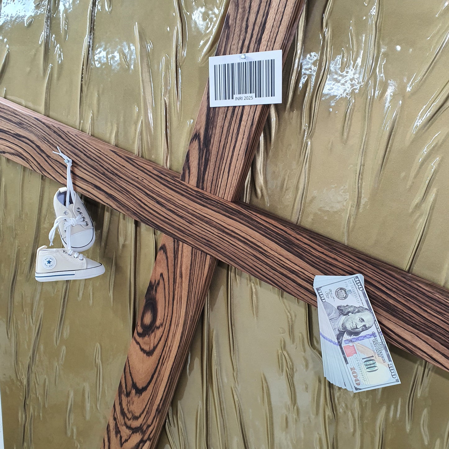 Il Settimo Comandamento mixed media artwork – close-up of cross pierced with baby shoes, dollar bills and red SOLD label