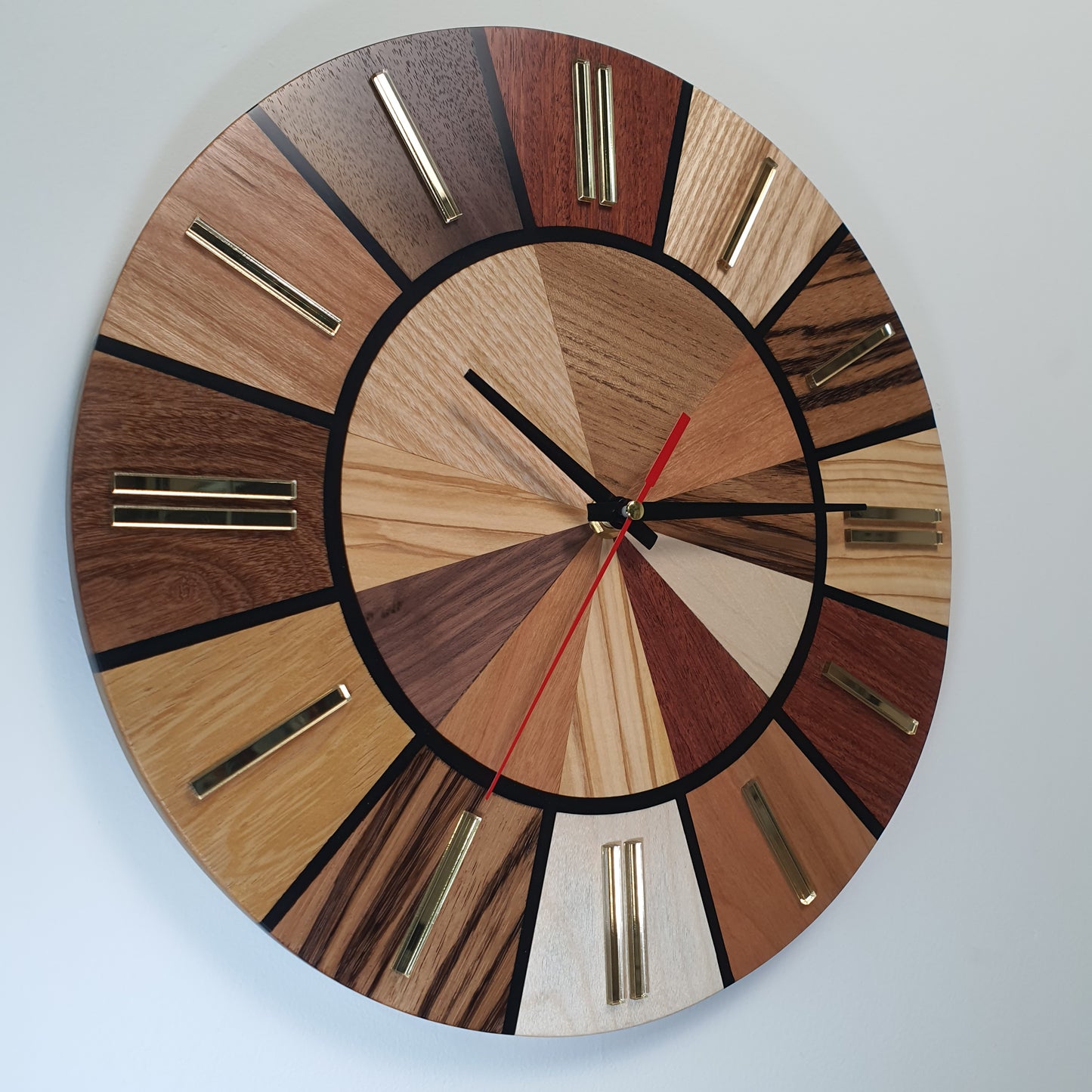 Side view of the Ten Woods Circle clock from the left showing layered wood textures and glossy finish