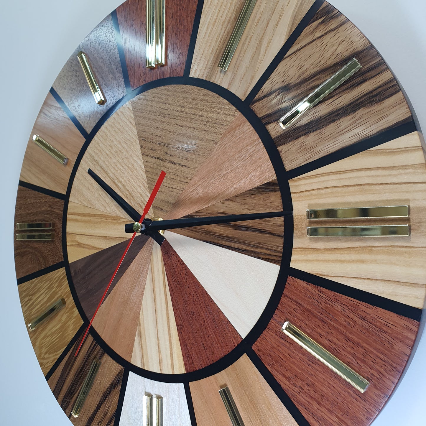 Close-up of the Ten Woods Circle clock face showing wood grain, black resin lines, and golden hour markers
