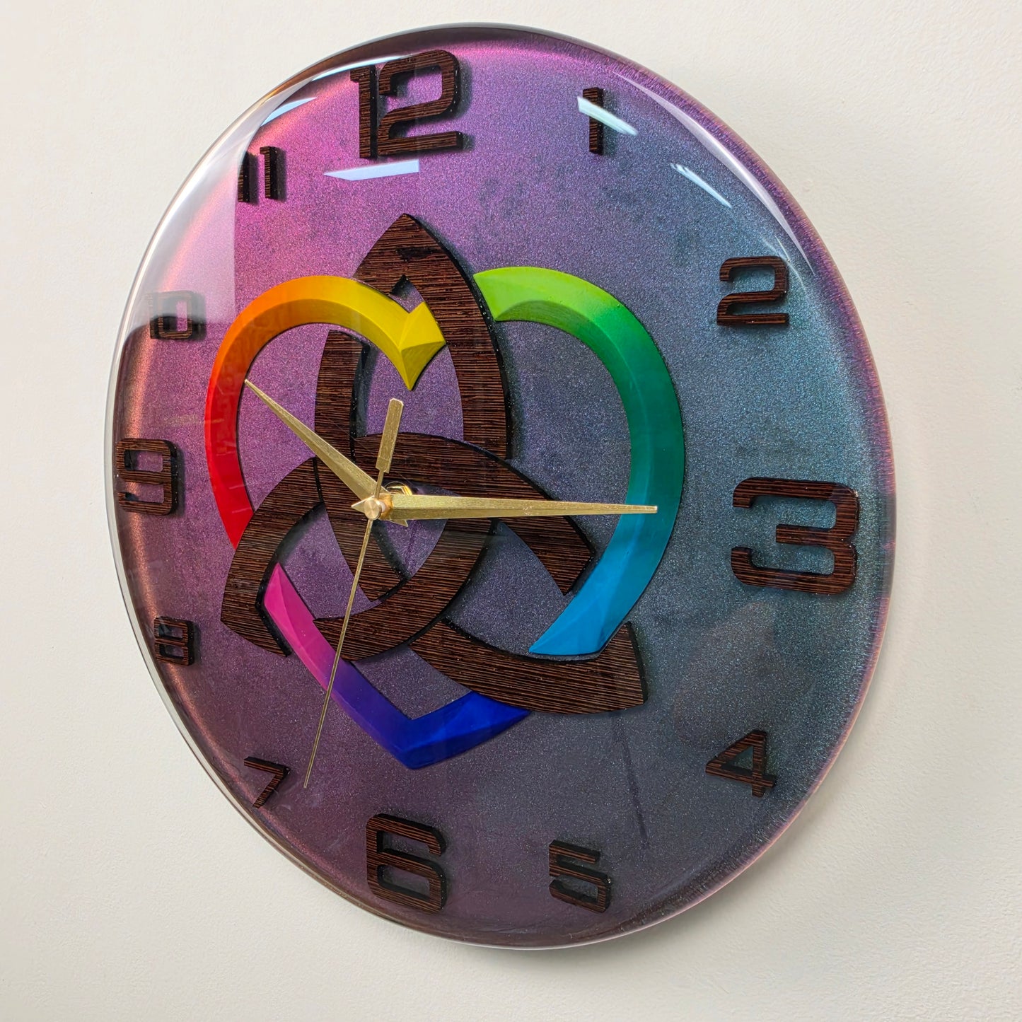 Timeless Symbols handcrafted wall clock made from epoxy resin and wenge wood, featuring a Triquetra symbol, rainbow heart, wooden numbers, and modern artistic design.