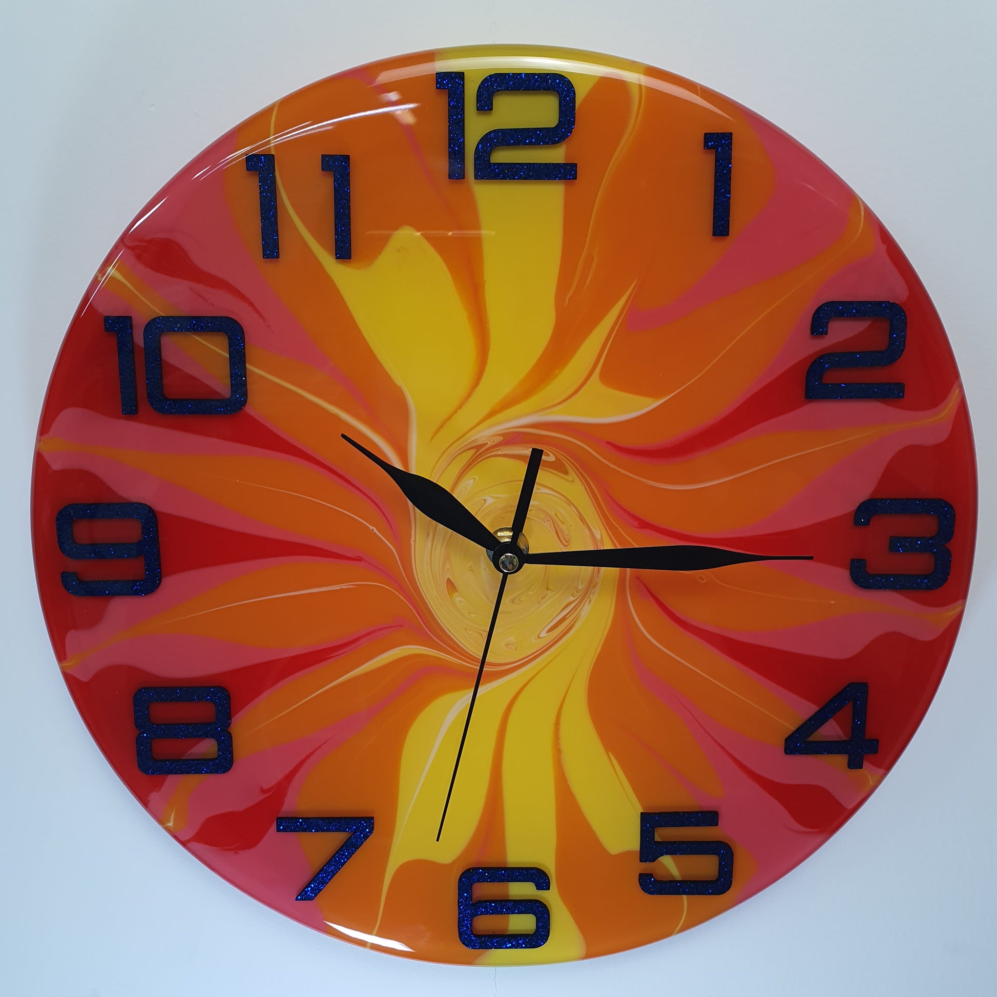 Front view of the "Fire Bloom" epoxy resin wall clock – bold swirling colors in red, orange, yellow, and pink