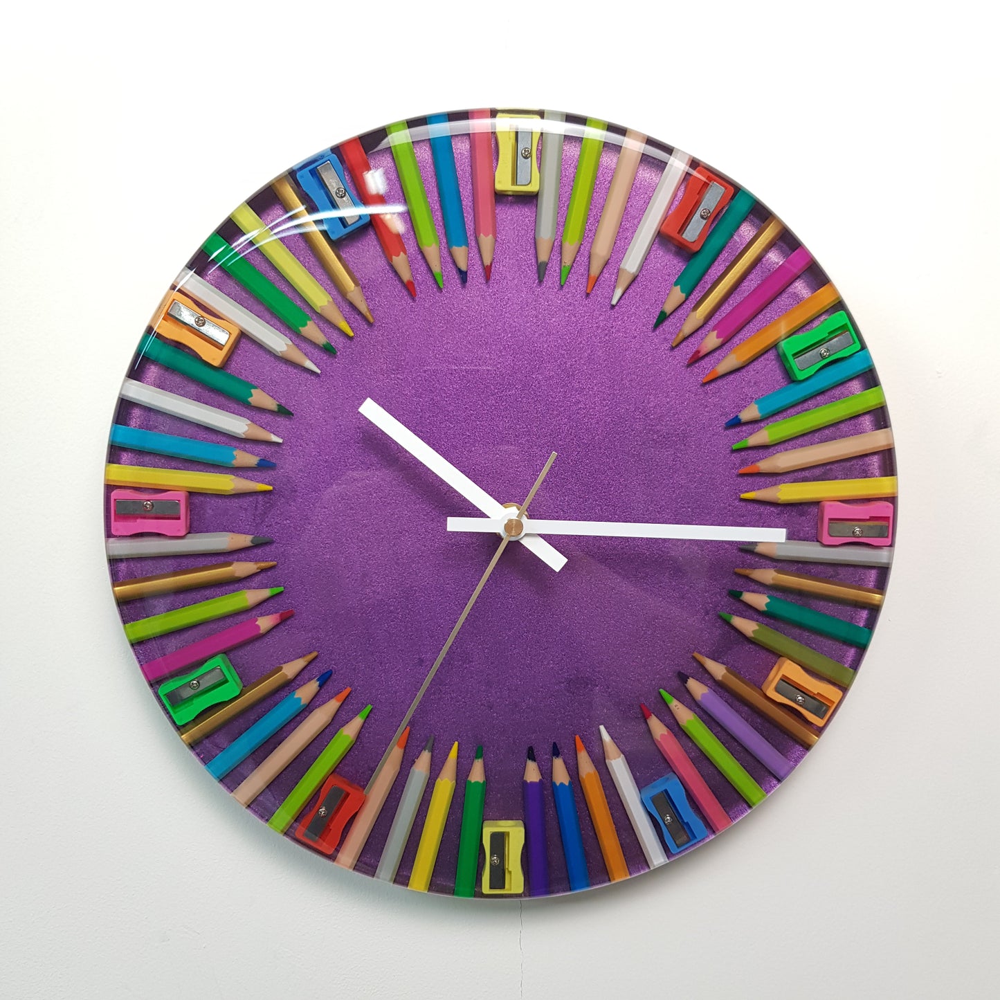 Front view of the “Chroma Balance” epoxy resin wall clock with coloured pencils and sharpeners