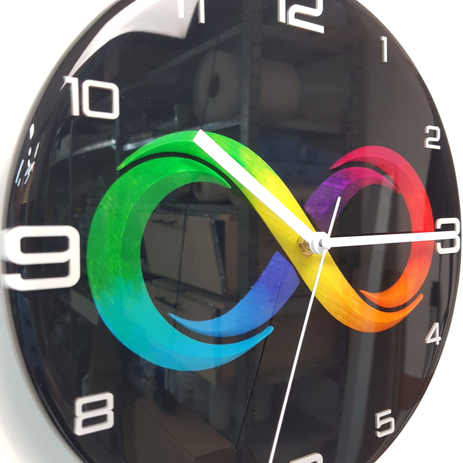 Close-up of the multicolor infinity symbol embedded in black resin with white hands and plexiglass numerals