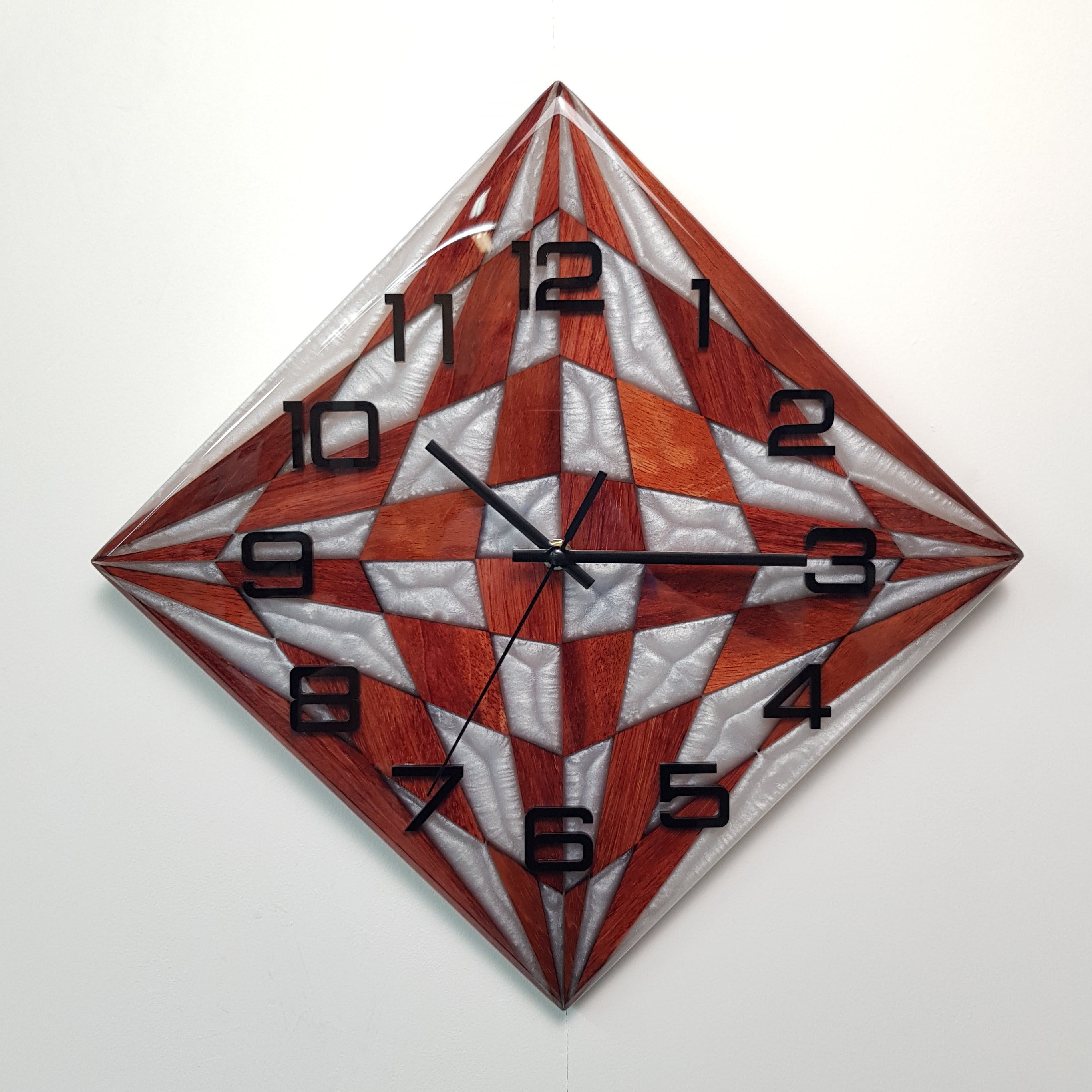 Front view of the Pearl Compass wall clock made from bubinga wood and pearly white epoxy resin