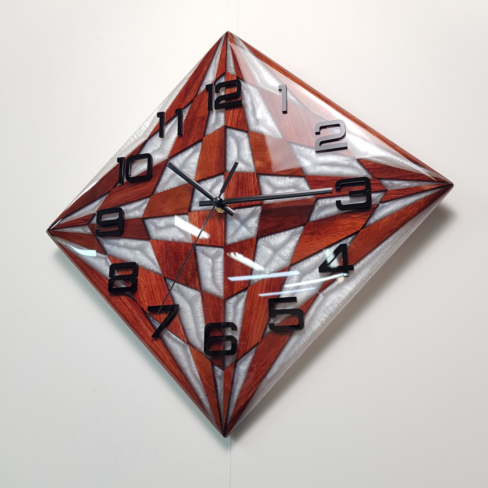 Angled close-up highlighting the pearly resin glow and modern black hands