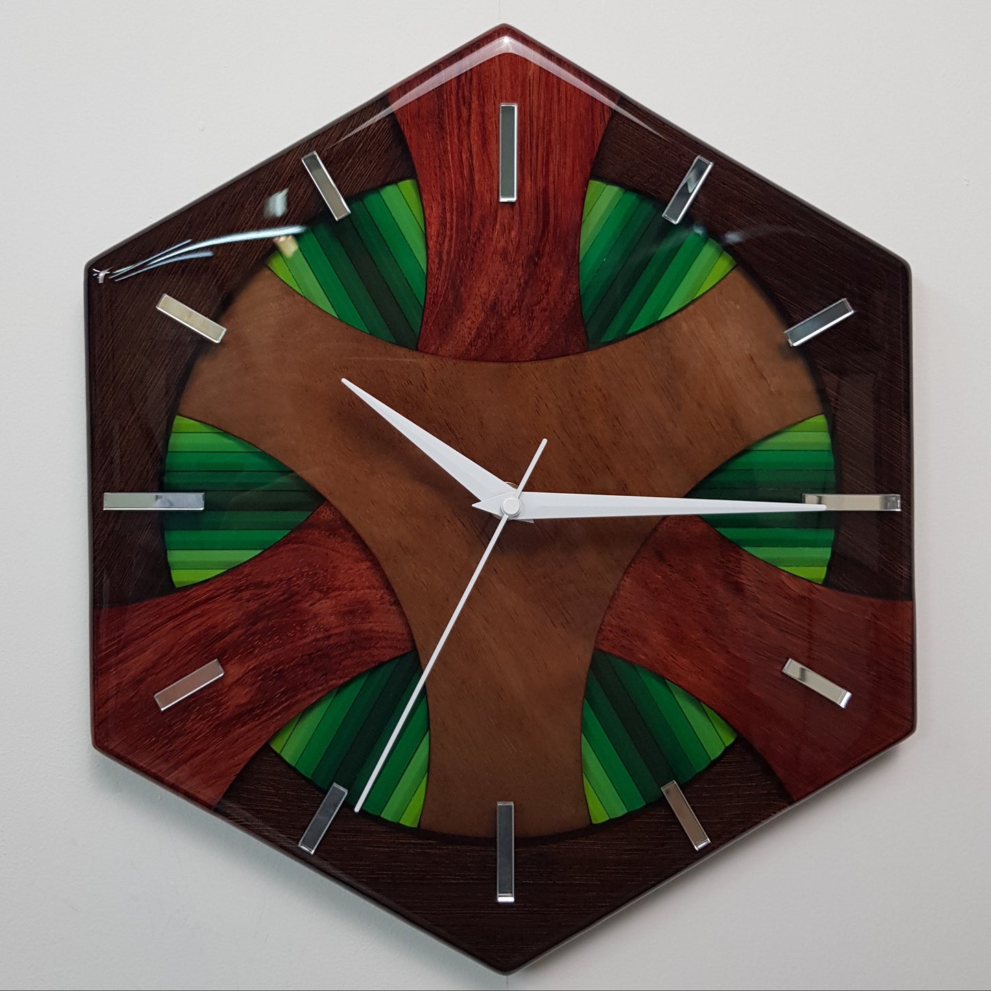 Front view of the “Forest Flow” hexagonal wall clock showing the wooden structure and green pencil details