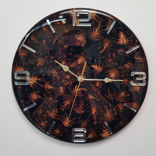 Front view of the “Pine Shadows” wall clock showing black resin, pine cones, and mirrored silver markers
