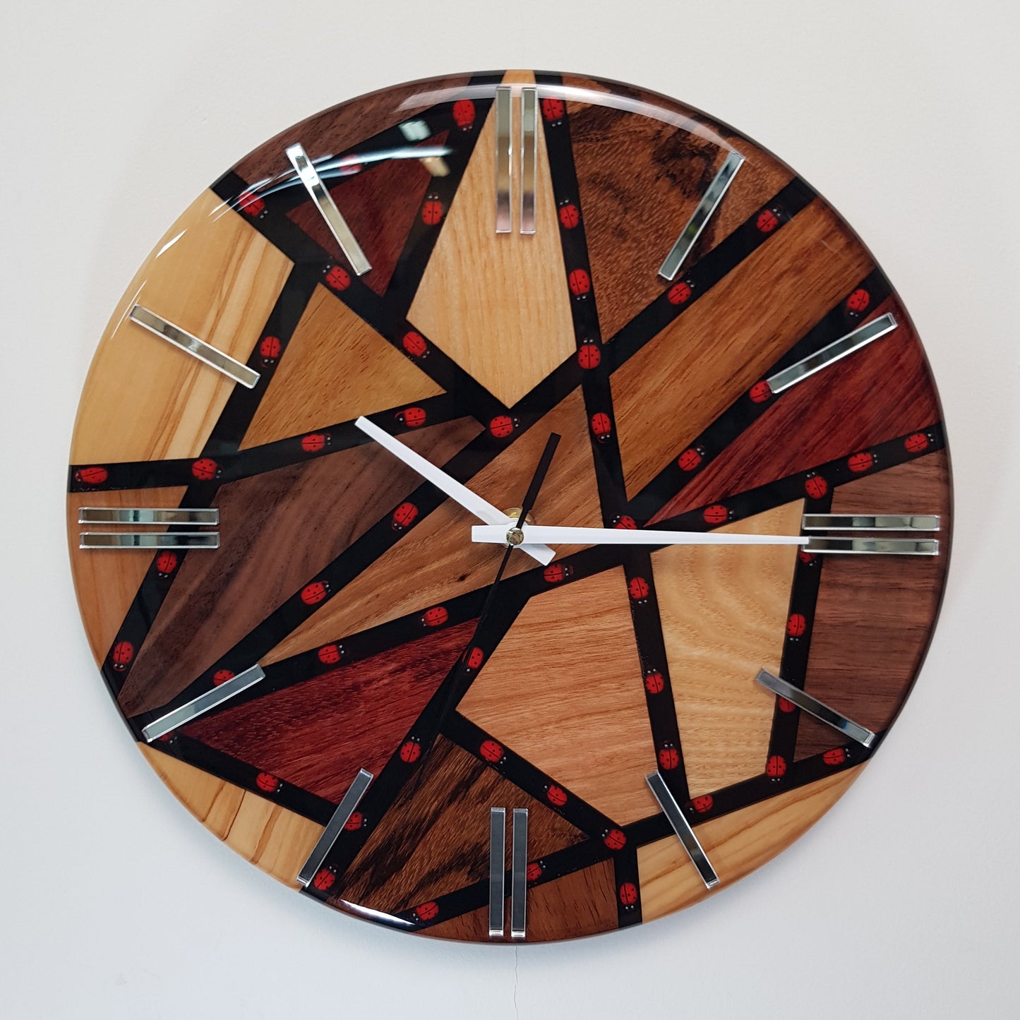 Front view of the “Ladybug Mosaic” wall clock showing the wood segments, black resin lines, and small red ladybugs