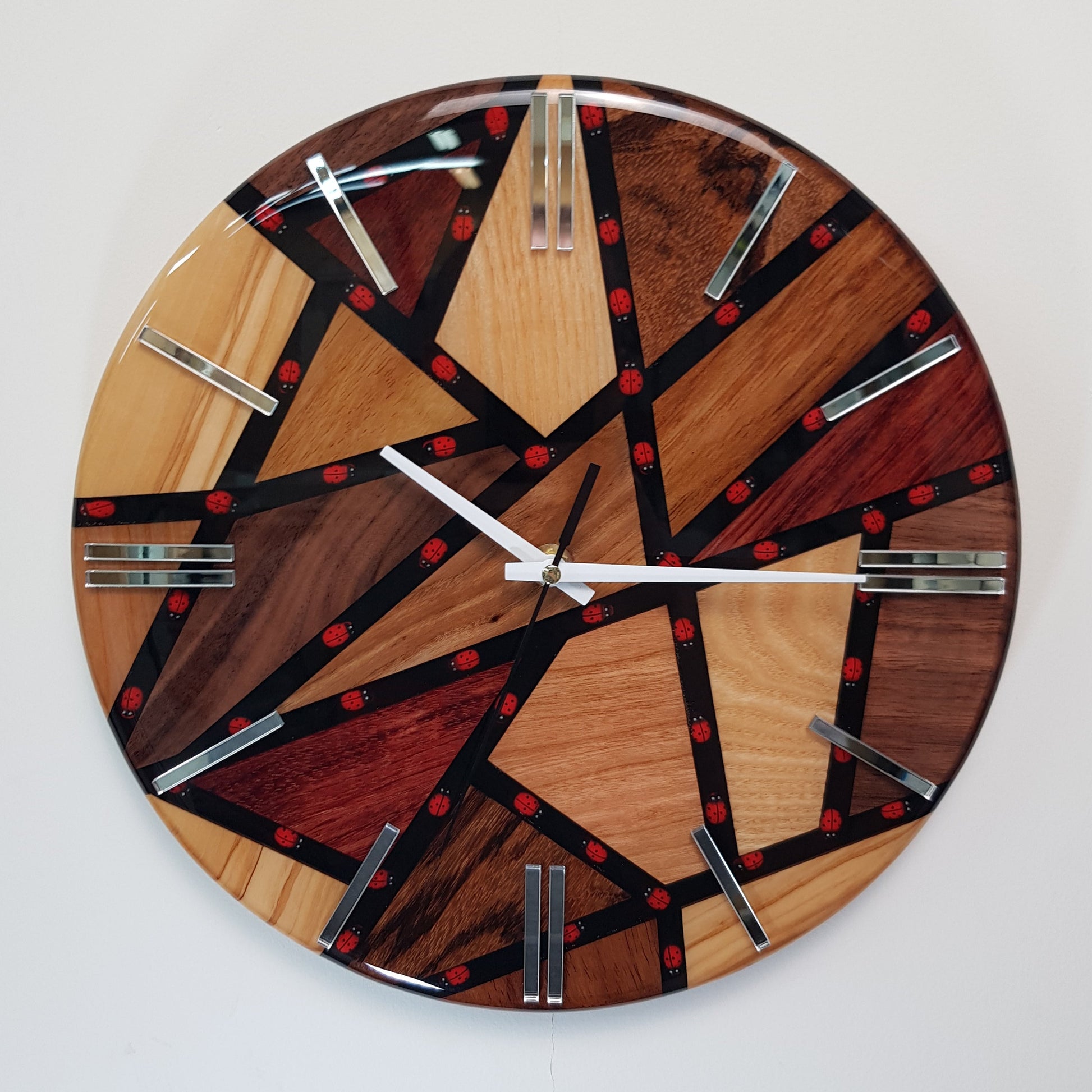 Front view of the “Ladybug Mosaic” wall clock showing the wood segments, black resin lines, and small red ladybugs