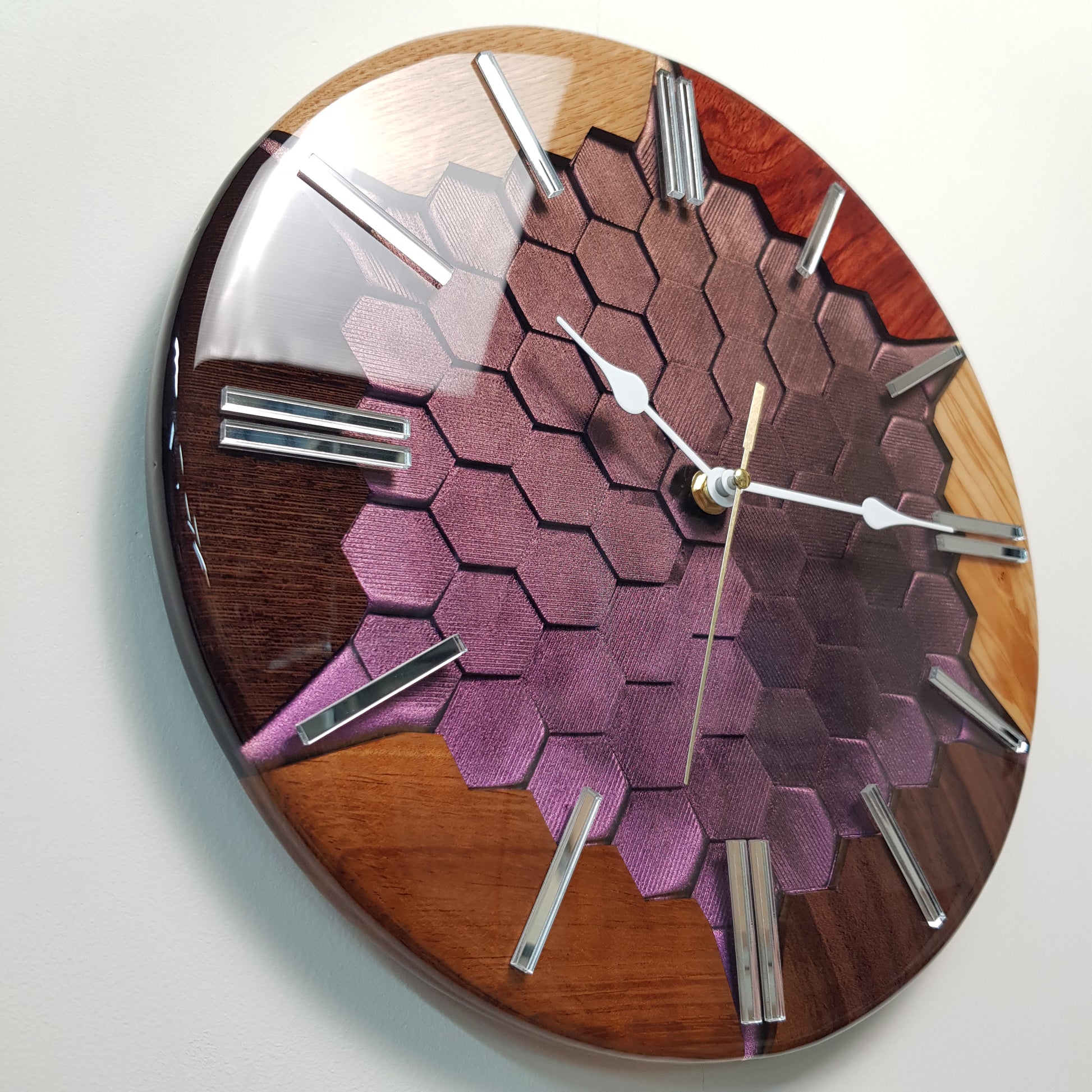 Full view of the clock on a light wall, showing multiple wood species and geometric center.