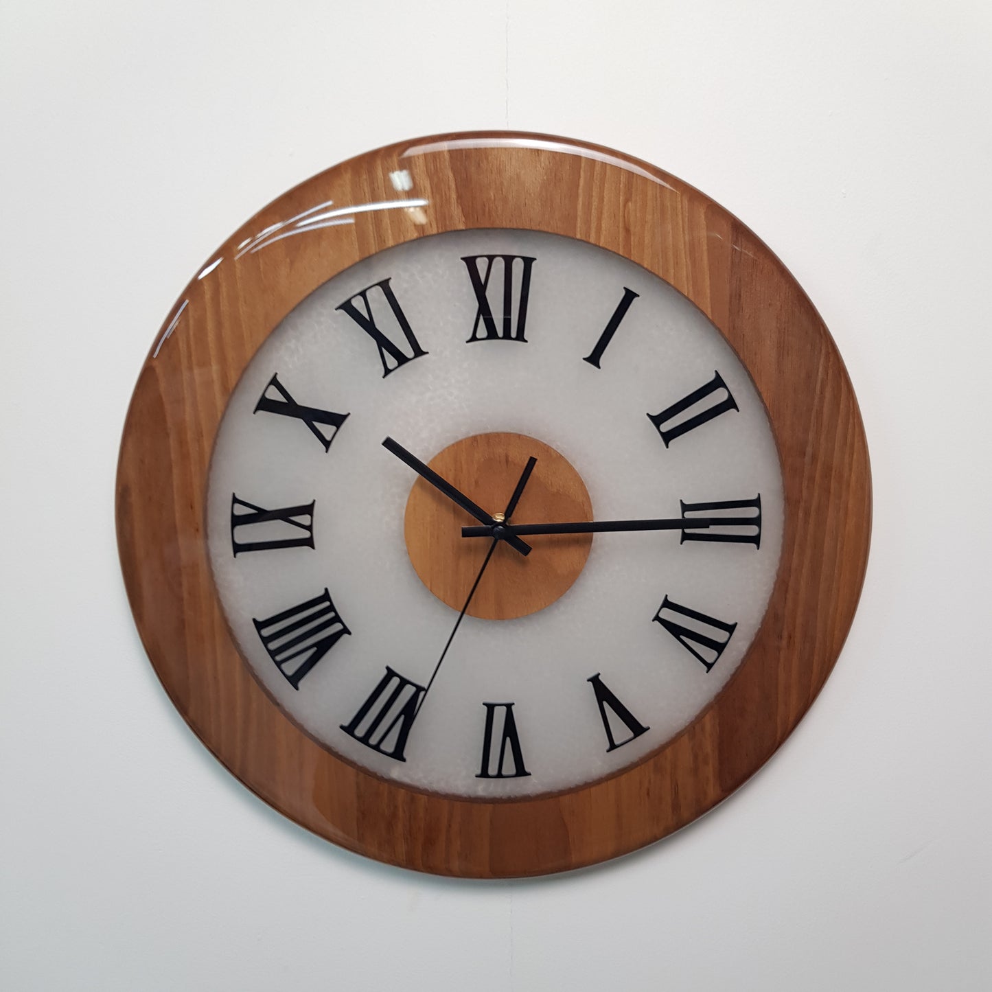 Walnut wood wall clock with Roman numerals and glowing center – front view.