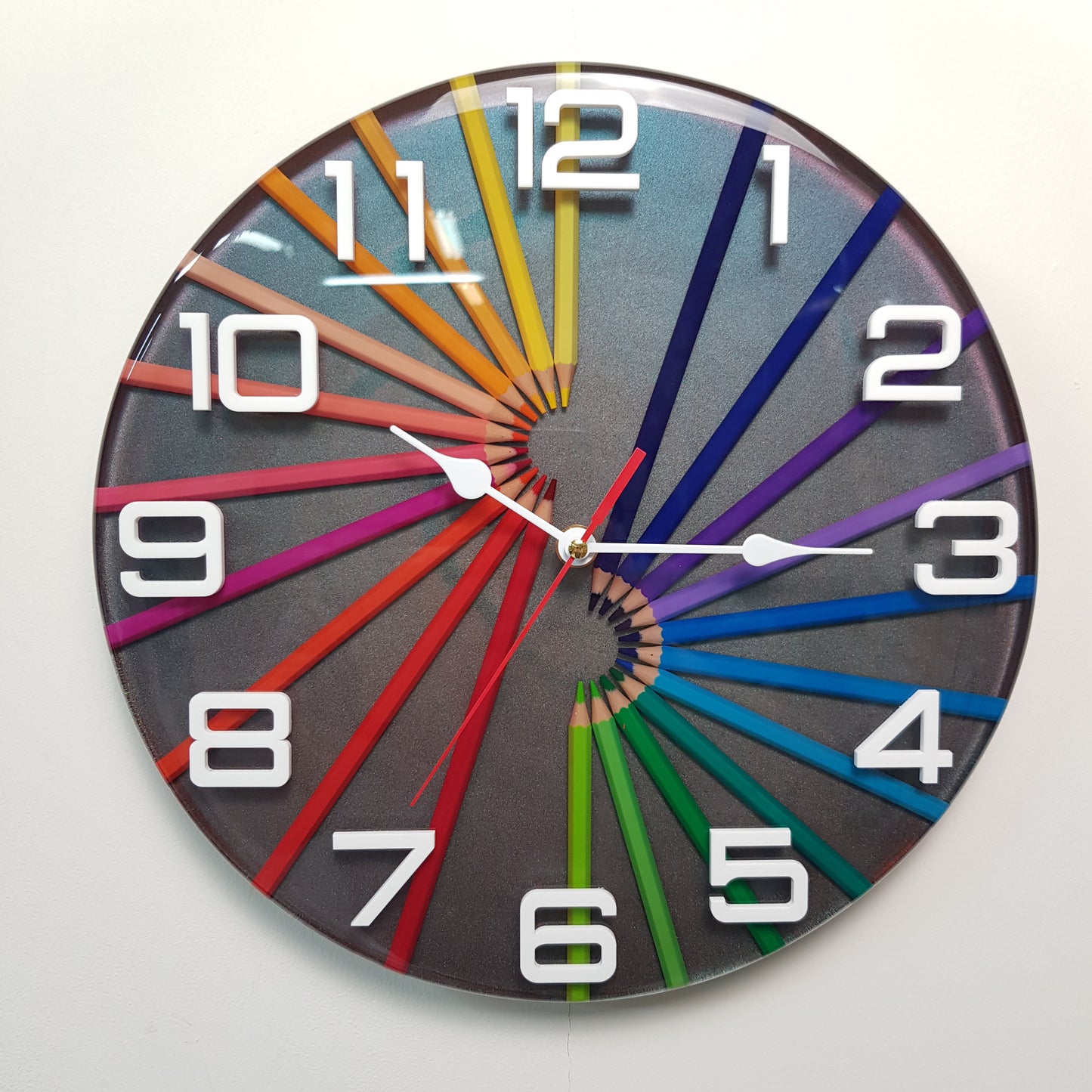Front view of the “Prismatic Spiral” resin clock – colourful pencils and chameleon background