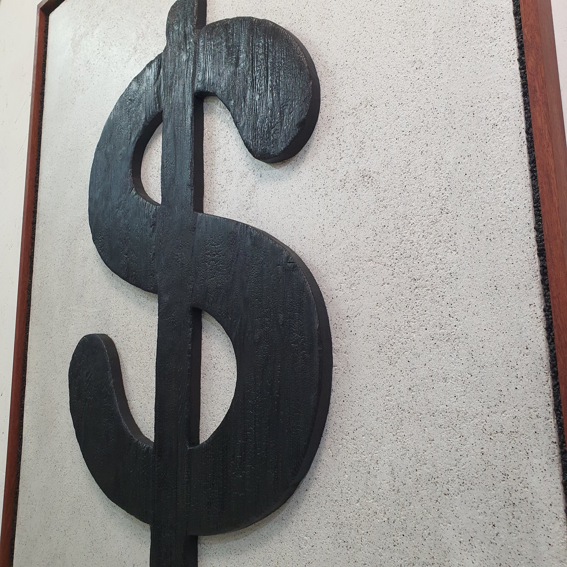Icona Bruciata resin and wood conceptual artwork – close-up of dollar symbol on textured mineral-like surface