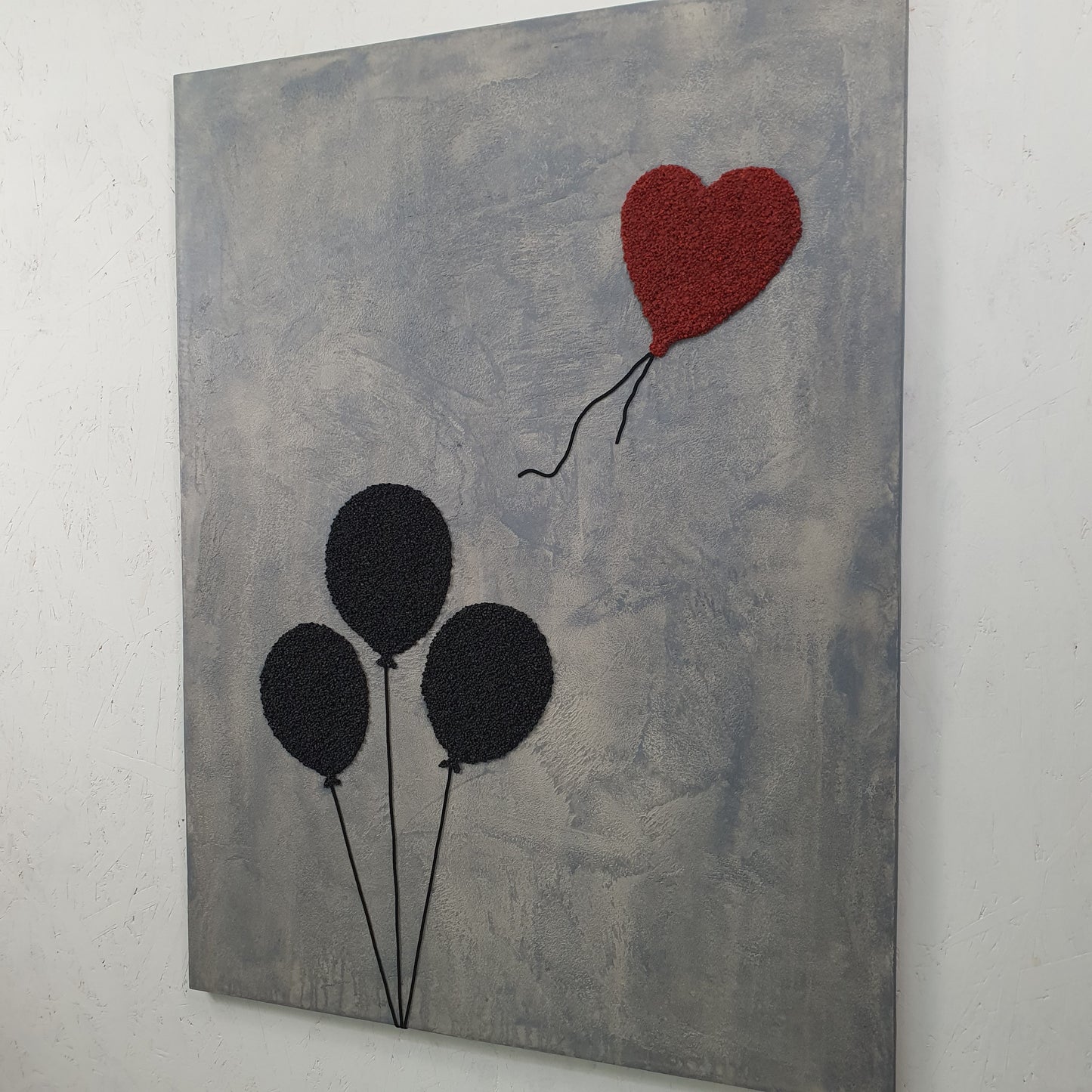 Ero con Loro resin and mixed media artwork – close-up of symbolic black balloons grouped together on grey surface