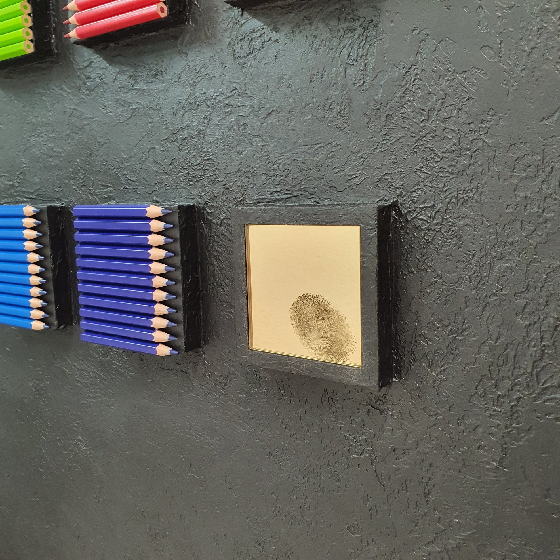 Identità Ordinata resin and plaster artwork – close-up of colorful blocks and golden mirror with fingerprint detail