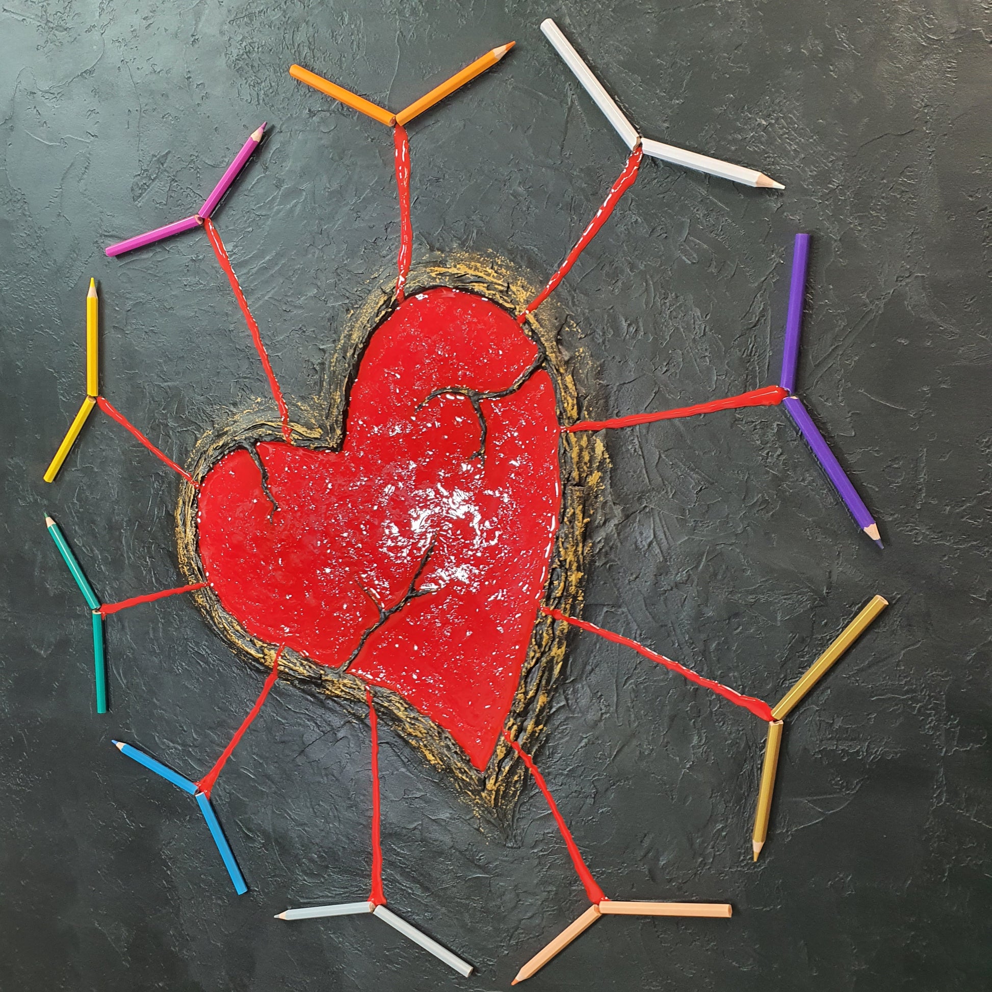 Ferito e Prezioso resin and pencil artwork – close-up of symbolic cracked heart surrounded by colored pencils