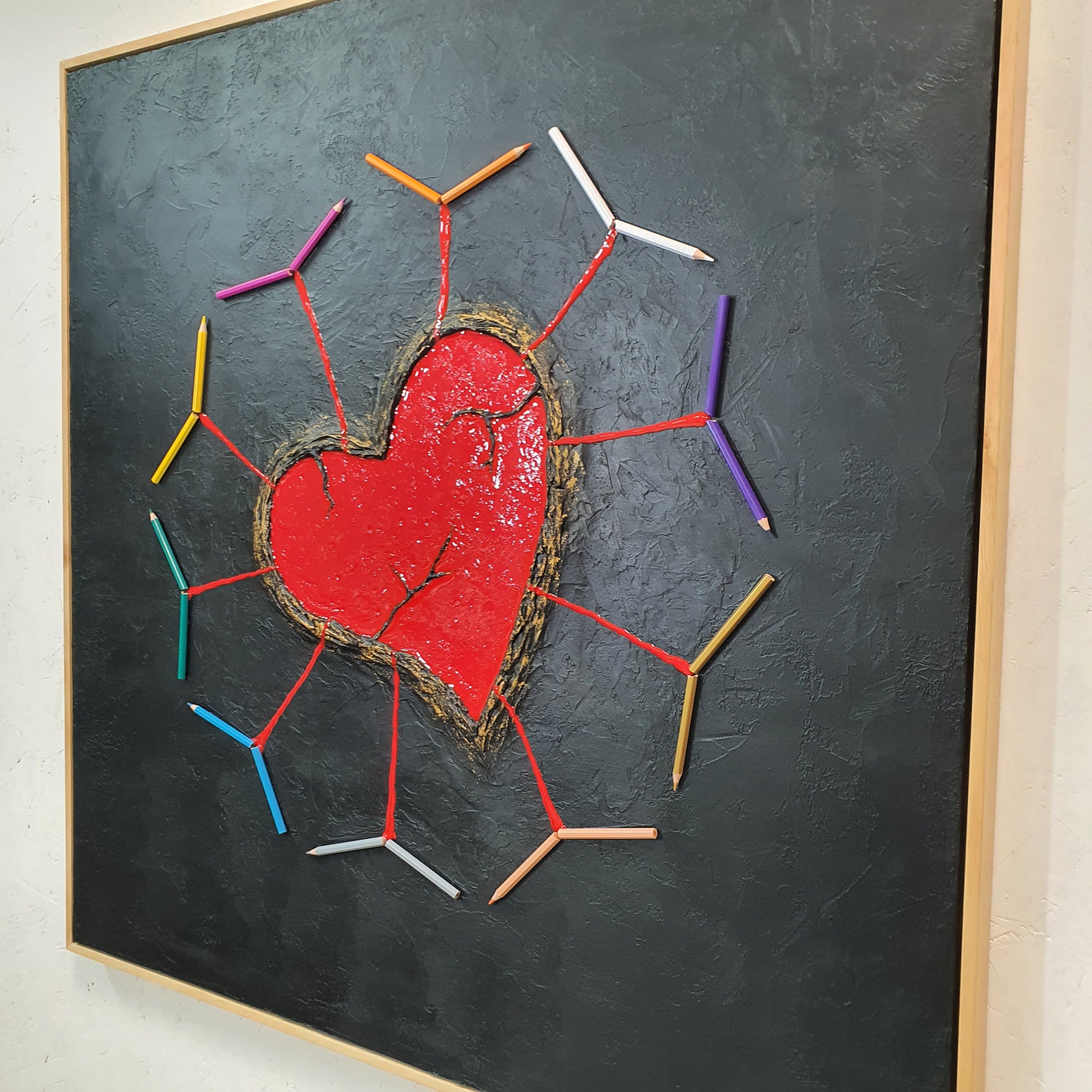 Unique contemporary art piece Ferito e Prezioso – handmade conceptual installation with wounded heart and vibrant pencils, angled photo