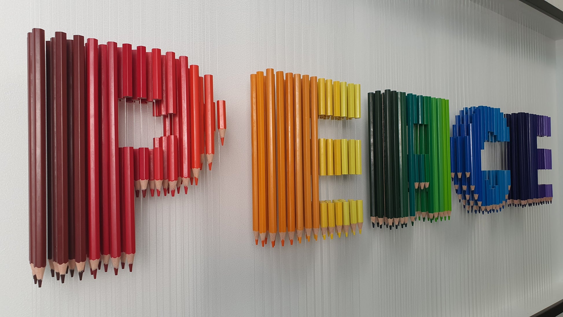Unique contemporary art piece Arcobaleno Sospeso – handmade 3D installation with resin pencils spelling PEACE, close-up
