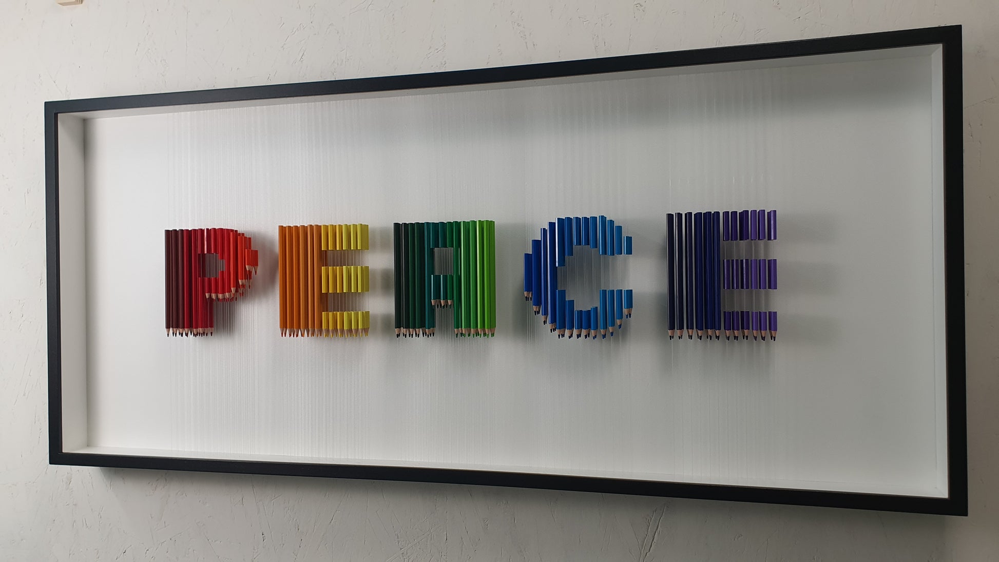 Arcobaleno Sospeso resin and pencil artwork – side view of suspended colorful letters in black frame