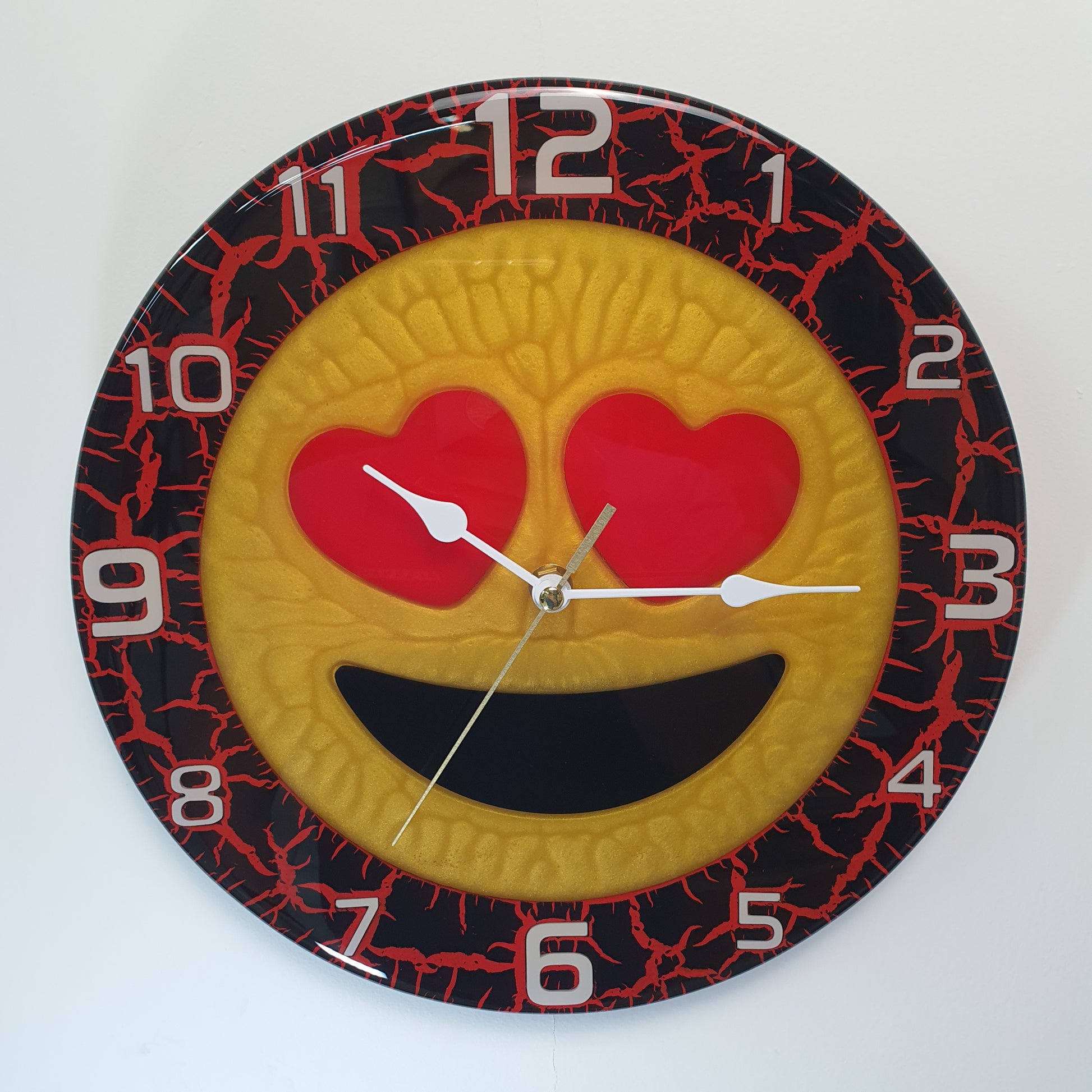 Close-up of Cuore Rosso resin wall clock with heart-eyes emoji and red crackle texture