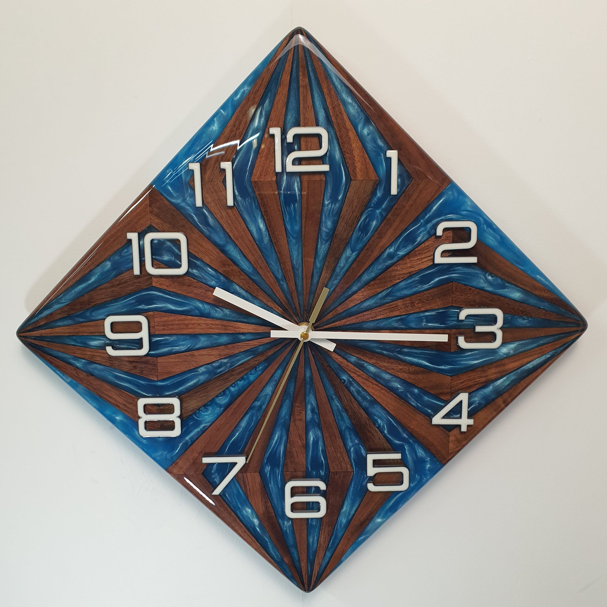 Front view of the “Walnut Wave” wall clock – handcrafted from walnut wood and blue epoxy, geometric sunburst pattern