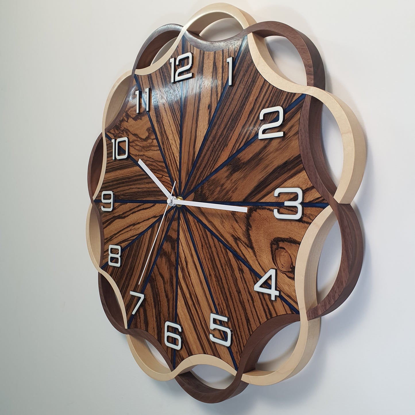 Side angle of the Crown Circle wall clock showing sculptural wavy wooden frame and layered craftsmanship.