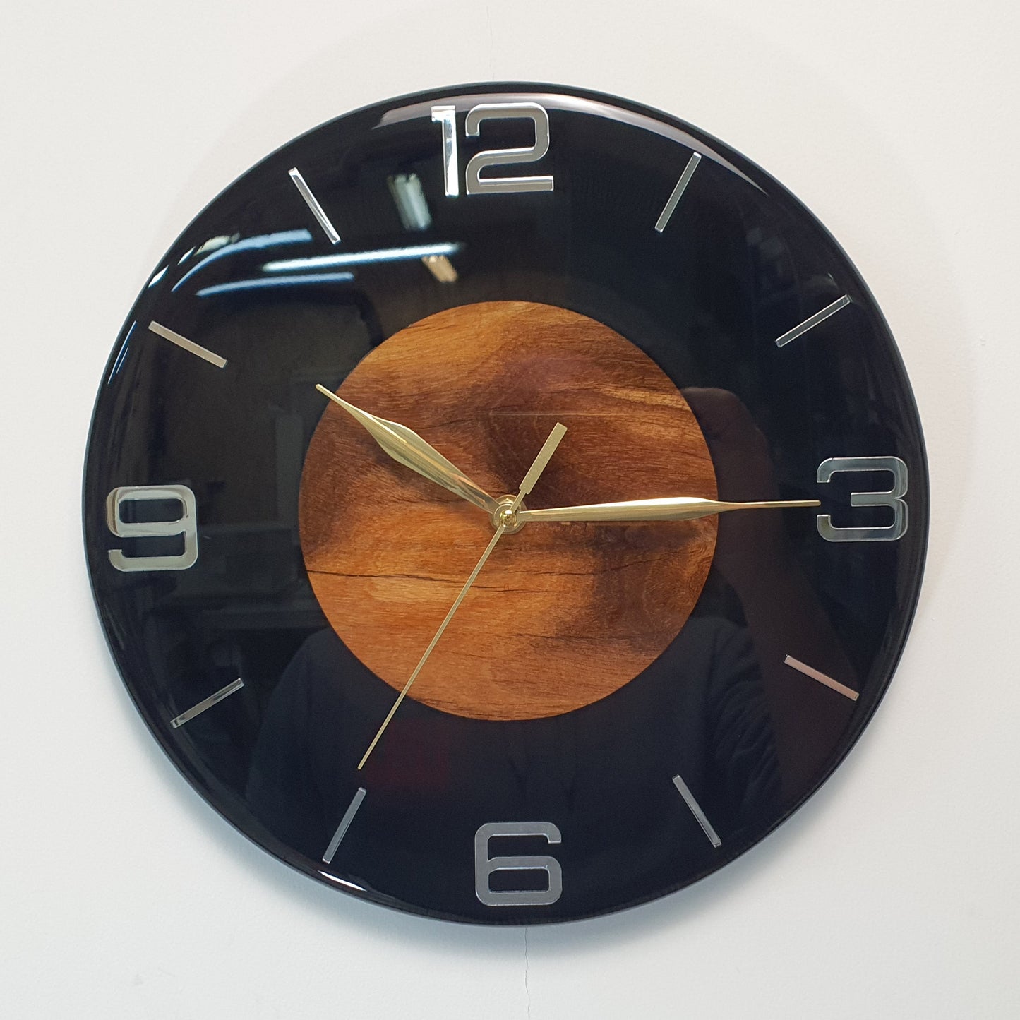 Front view of the “Dark Core” resin and wood wall clock showing the black glossy surface and wooden center