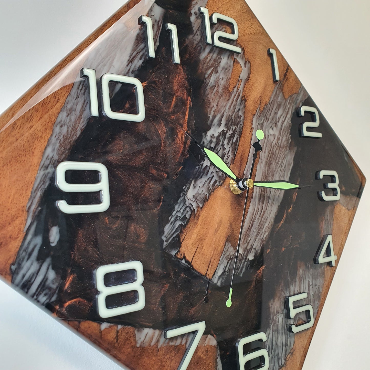 Close-up of the walnut wall clock revealing fluorescent resin lines and glowing numerals on the smooth, glossy surface.