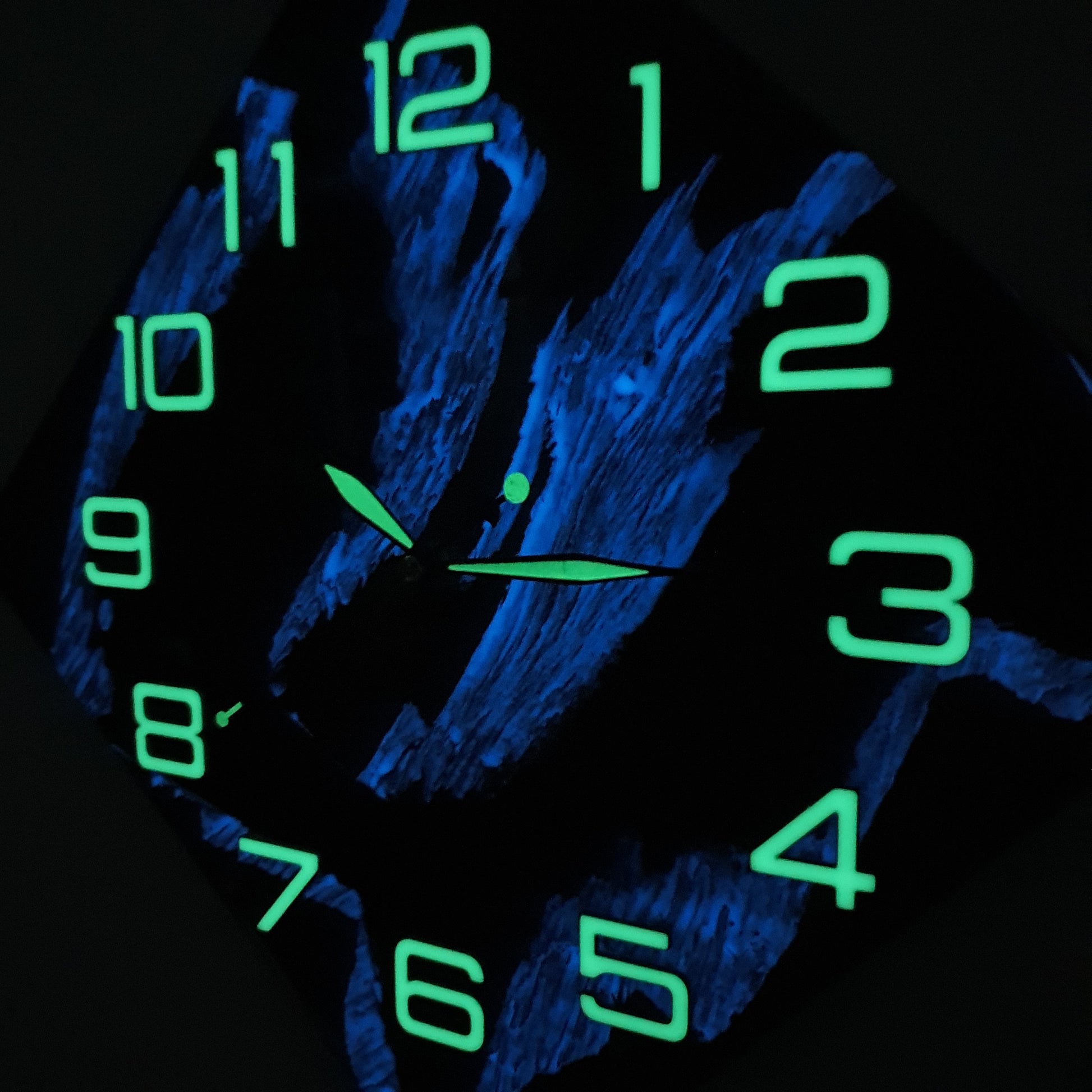 Walnut wood wall clock glowing in the dark with luminous green numbers and hands, showing its fluorescent resin details.