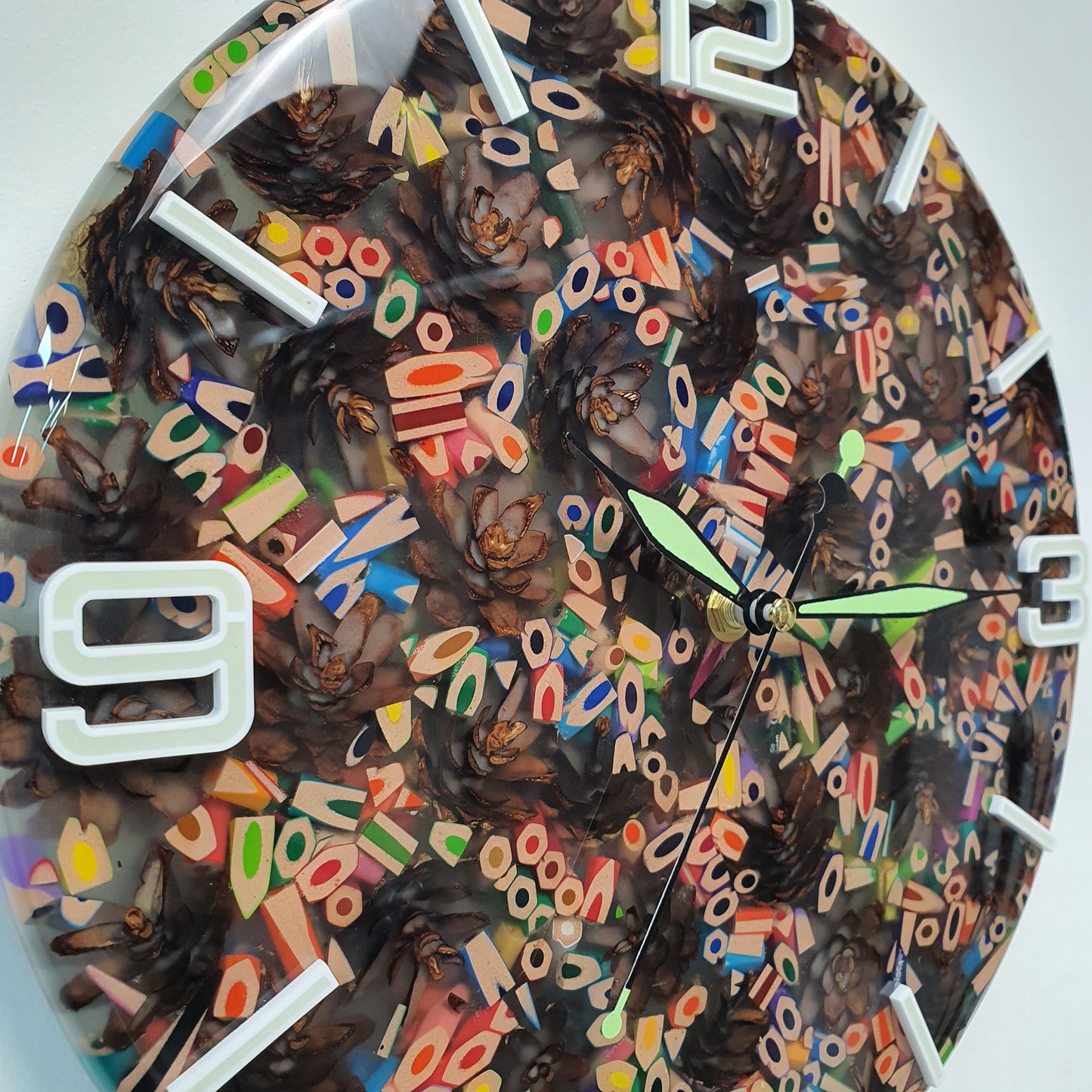Close-up of the colorful pencil fragments and natural pinecones encapsulated in glossy resin, showing the fluorescent-filled numbers.