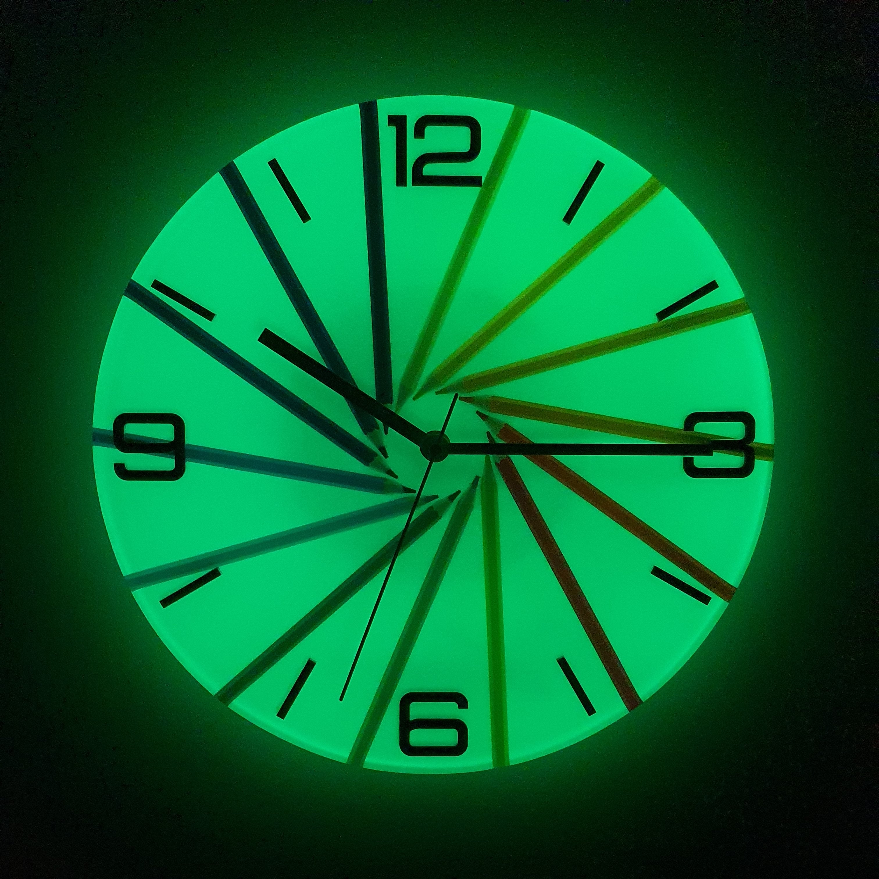 Front view of Neon Spiral wall clock glowing in the dark with fluorescent pigment