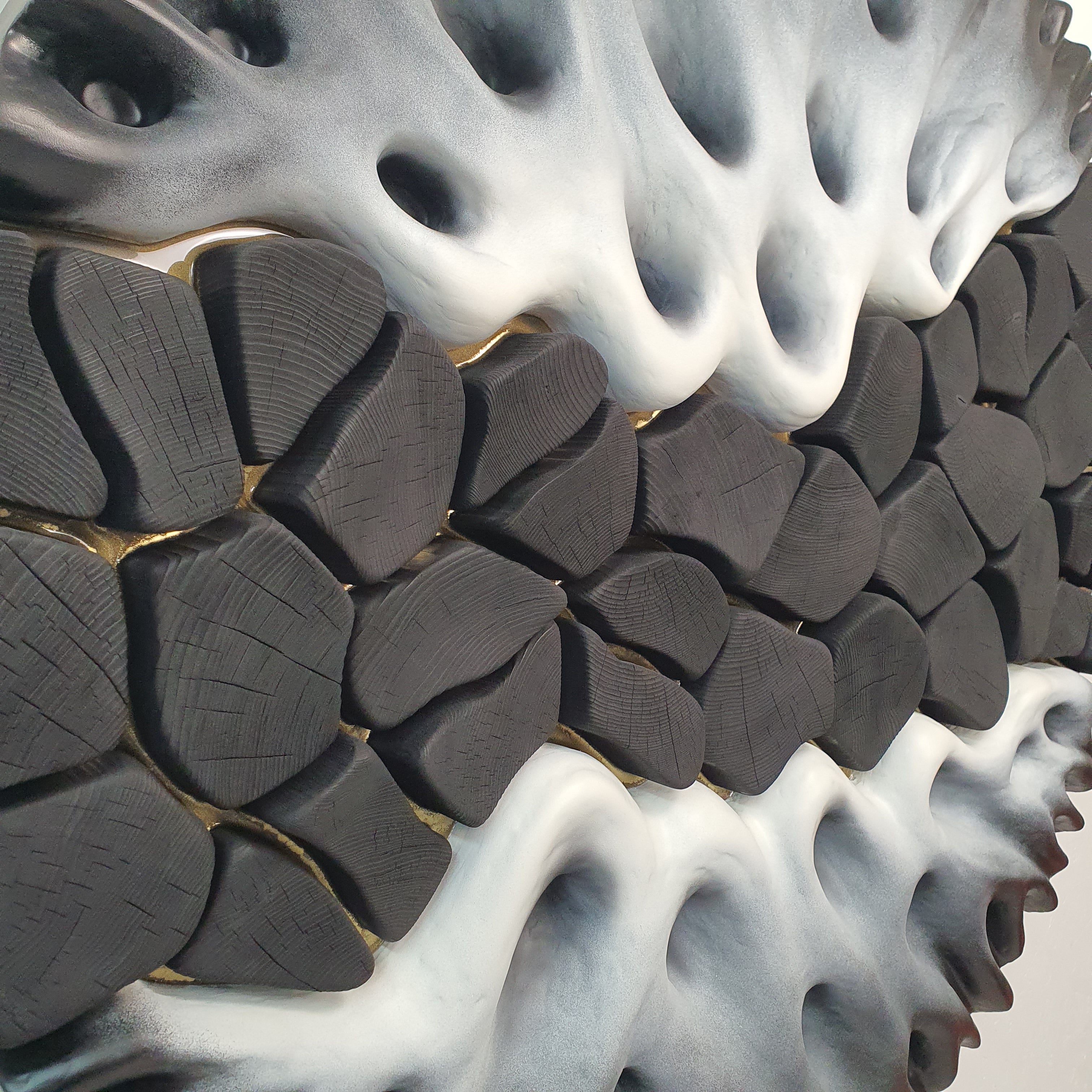 Close-up of black textured wood elements with gold resin lines in wall sculpture