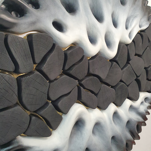 Close-up of black textured wood elements with gold resin lines in wall sculpture