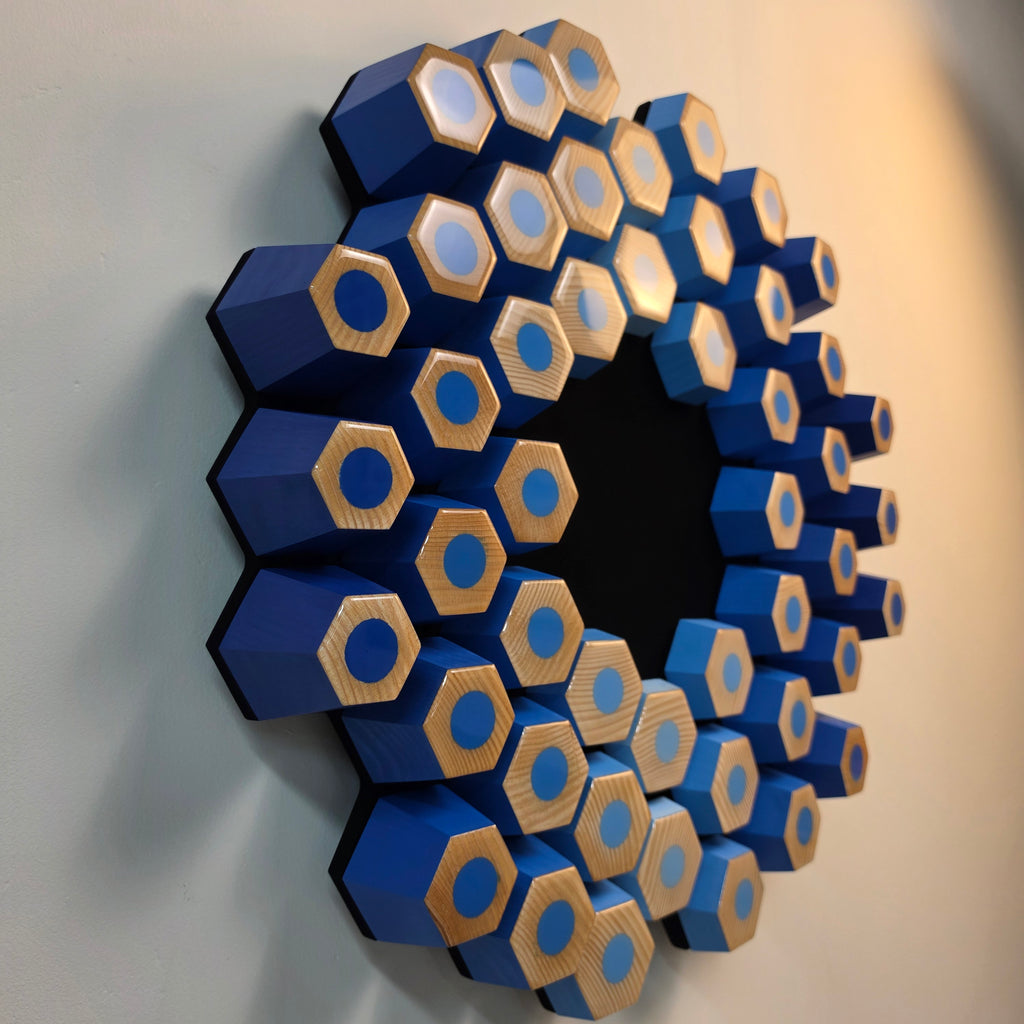 Modern 3D wall artwork with layered blue geometric modules and light-absorbing black center