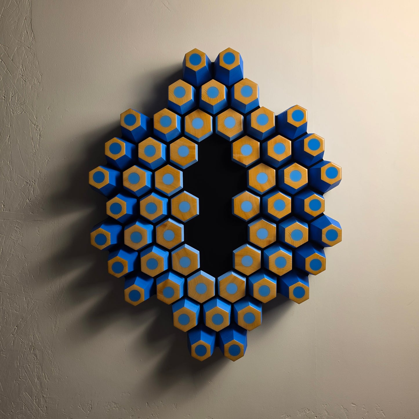 Orbita wall sculpture from the Profondità series featuring blue geometric forms and a light-absorbing black center