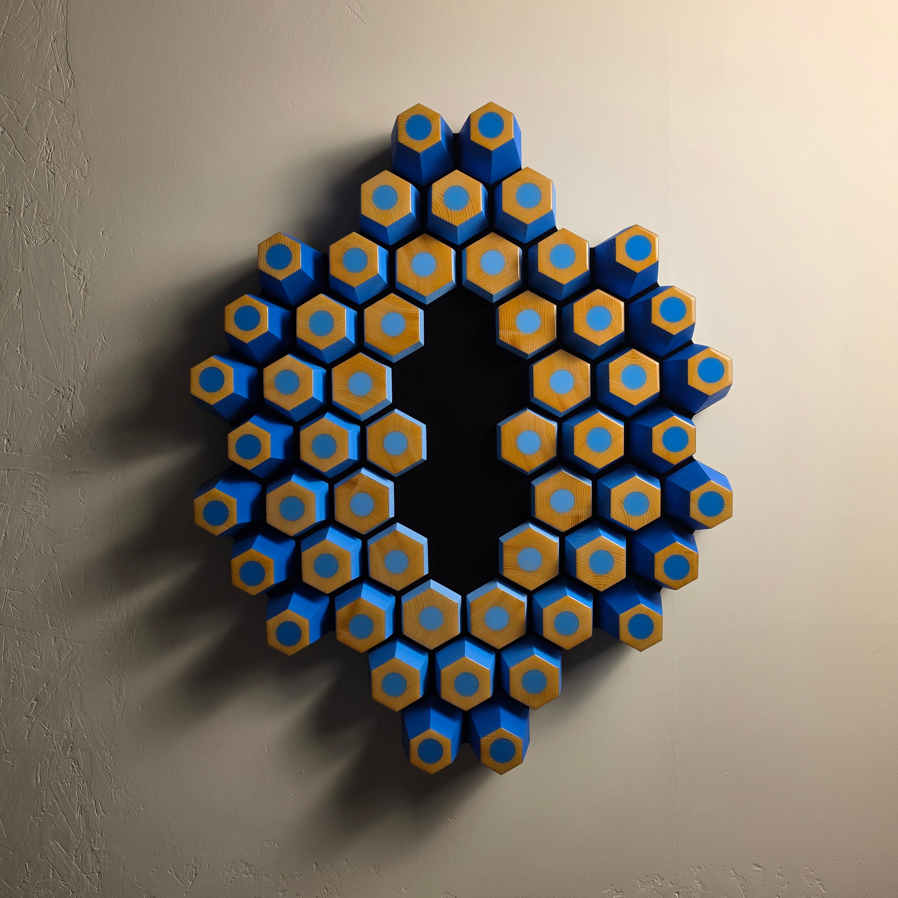 Orbita wall sculpture from the Profondità series featuring blue geometric forms and a light-absorbing black center