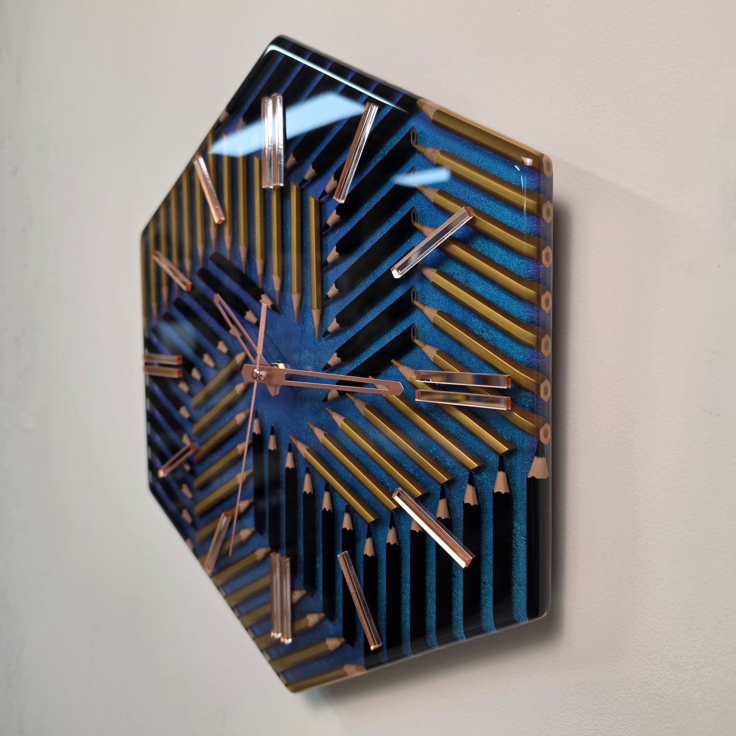 Modern resin wall clock featuring black and gold colored pencils in a hexagonal pattern
