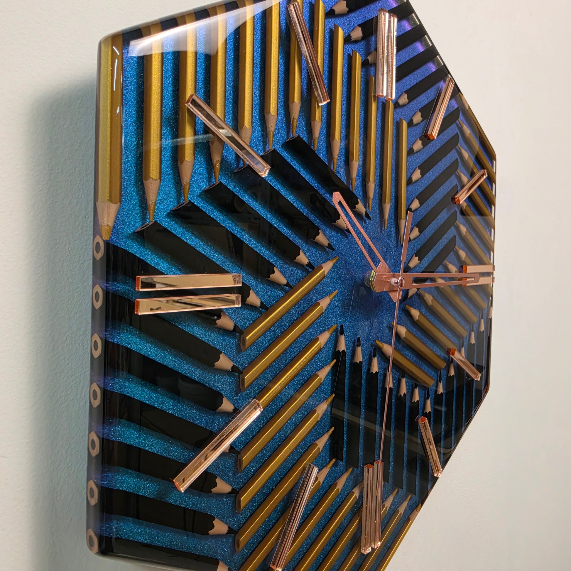 Hexagonal epoxy resin wall clock with black and gold pencils and rose-gold mirrored markers