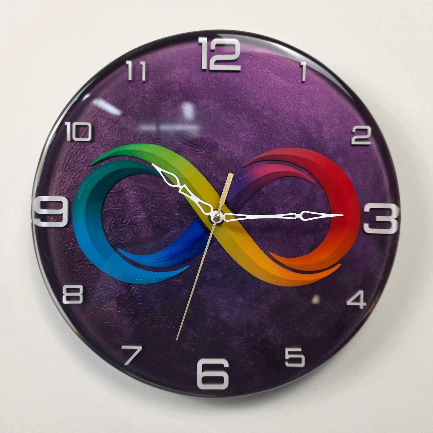 Decorative epoxy resin wall clock from the Timeless Symbols collection featuring a colorful infinity motif