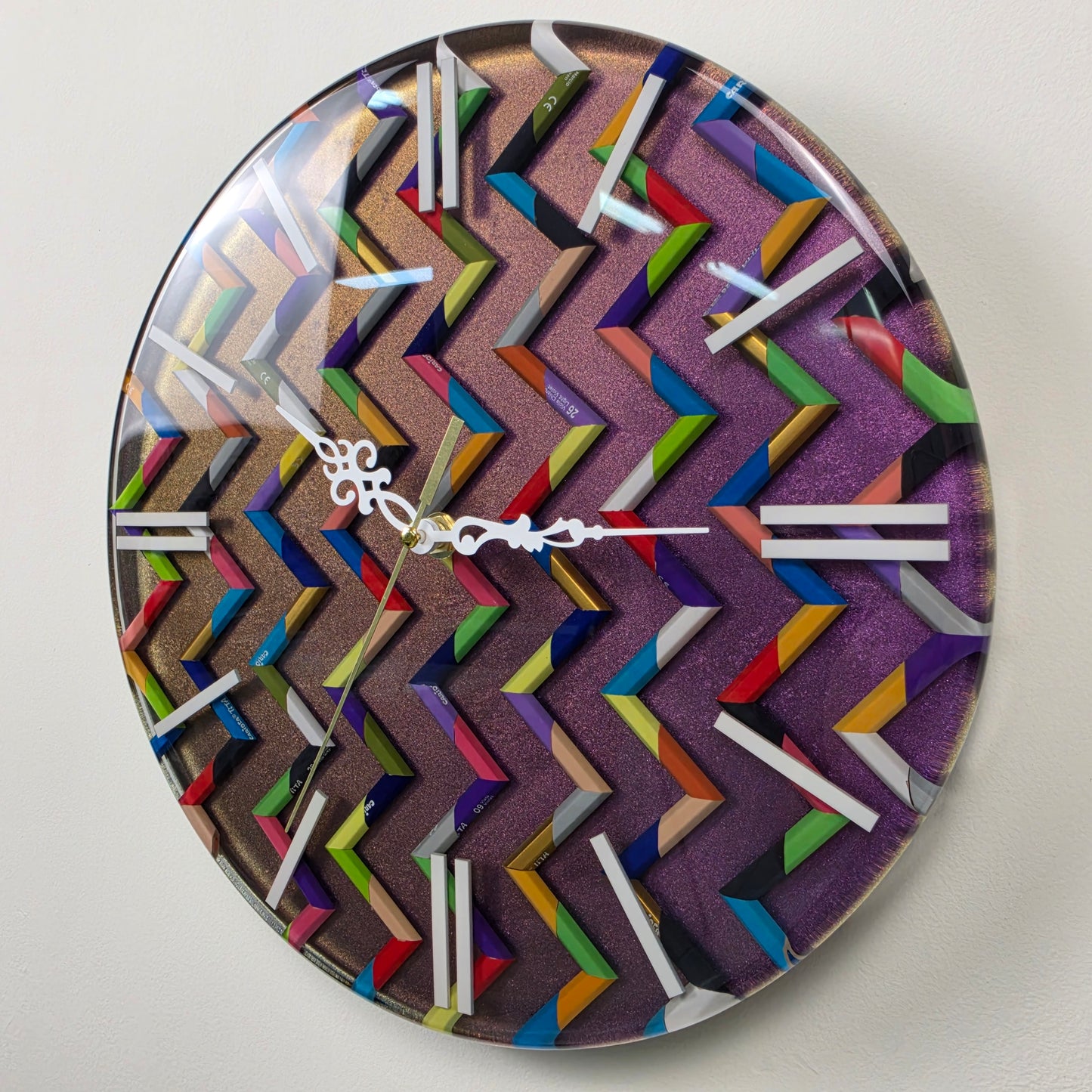 Modern geometric wall clock featuring colorful pencils, shimmering metallic background and glossy clear resin surface.