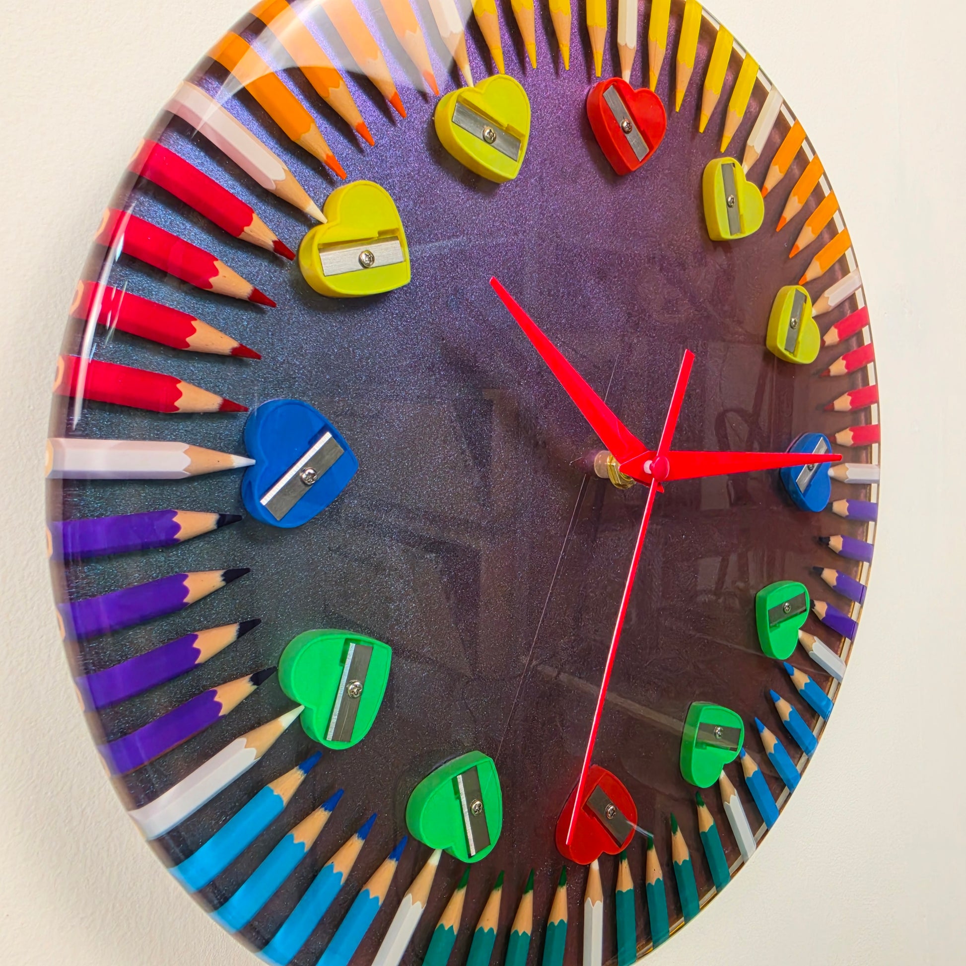 Unique Studio Colors wall clock featuring real colored pencils, heart-shaped sharpeners, and glossy epoxy resin.