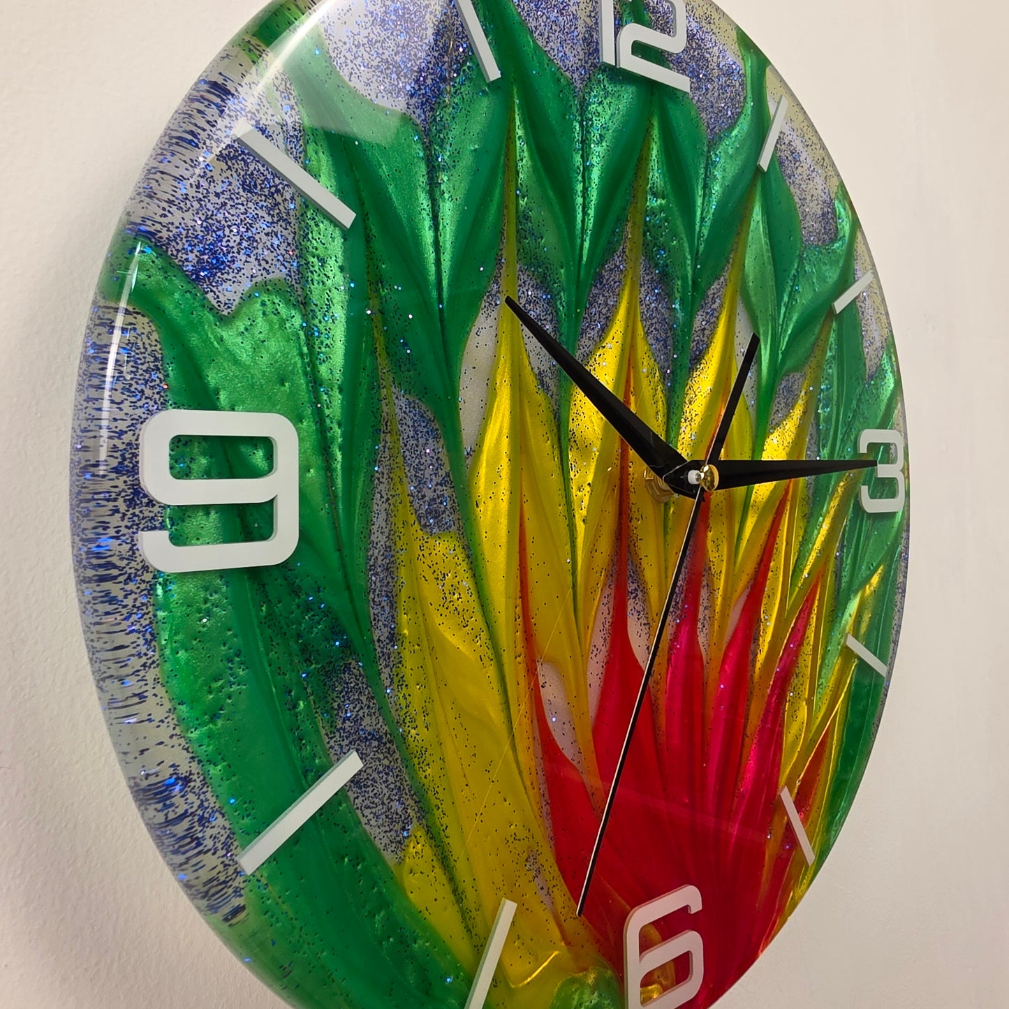 Modern 30 cm resin wall clock featuring an original color-blending technique, embedded white acrylic numbers, blue glitter accents, and a silent quartz movement.