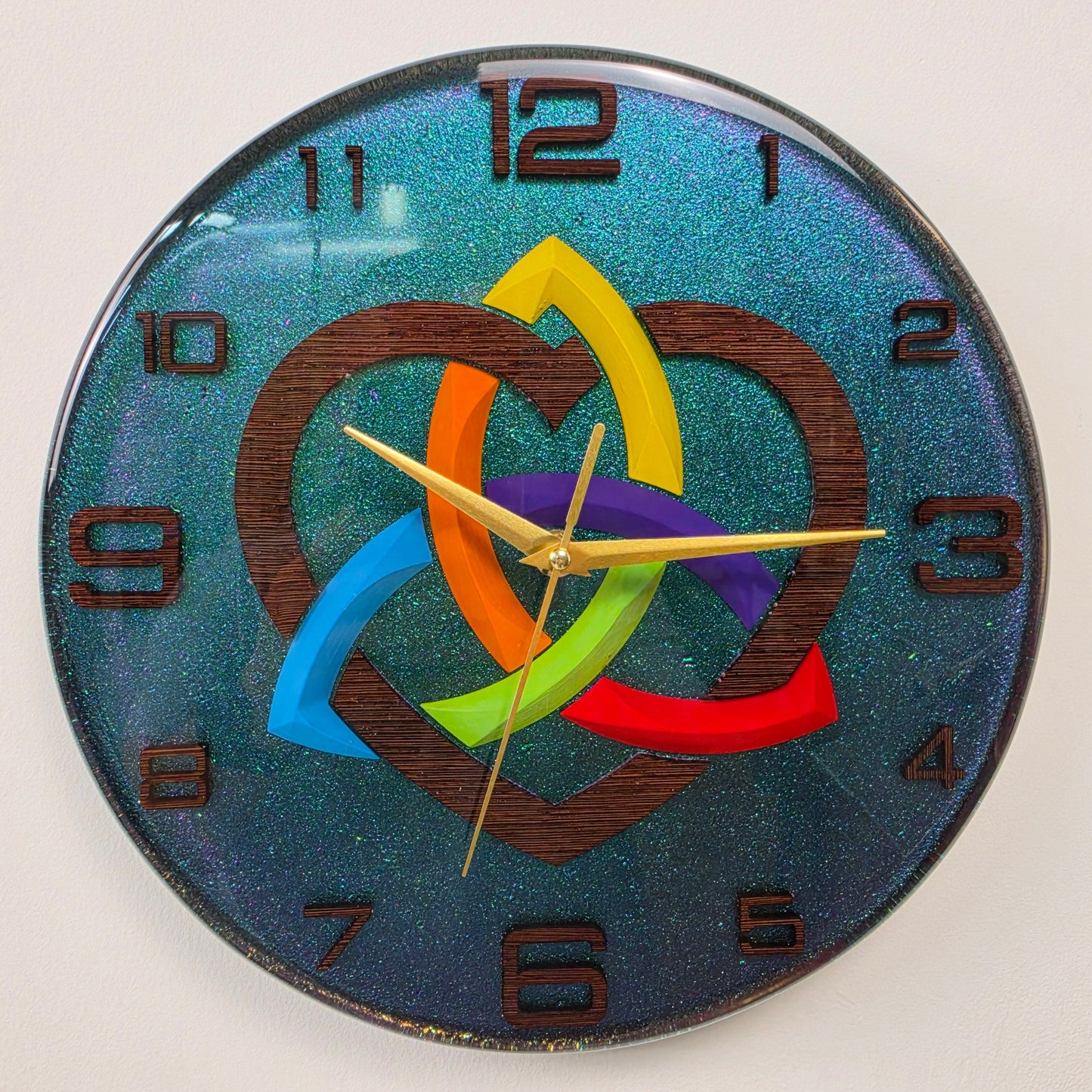 Artistic epoxy resin wall clock V2 with a wenge wood Celtic knot, rainbow heart centerpiece, silent sweep movement, and iridescent chameleon effect.