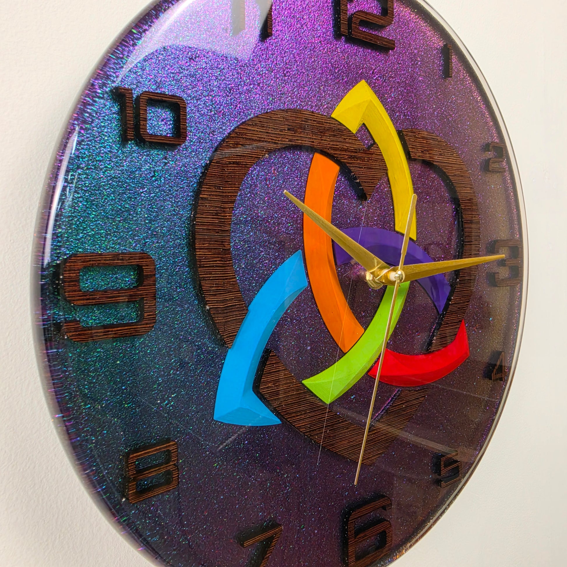 Modern resin wall clock with a handcrafted wenge wood Triquetra V2, rainbow-colored heart, wooden numbers, and silent quartz movement.