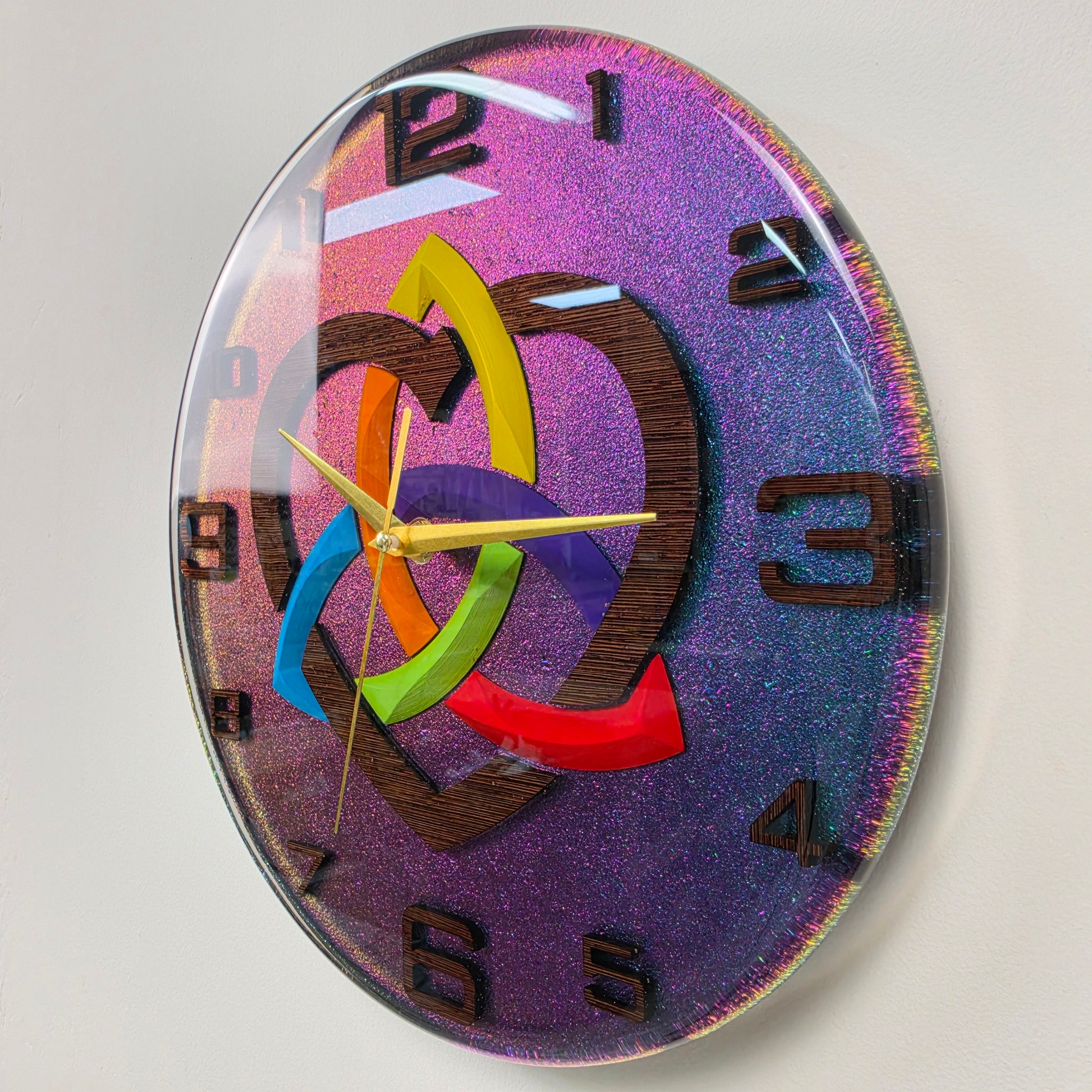 Unique 30 cm epoxy resin wall clock inspired by the ancient Triquetra symbol V2, combining handcrafted wenge wood with a shimmering chameleon finish.