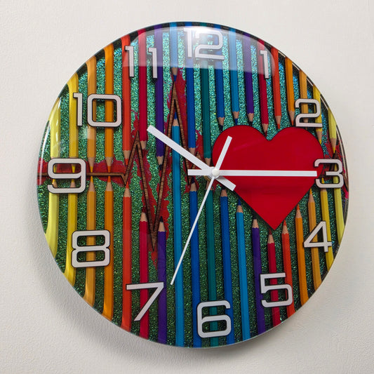 Handcrafted epoxy resin wall clock featuring colorful pencils, a heartbeat line, and a red heart on a chameleon background with white acrylic numbers from the Studio Colors collection V2.