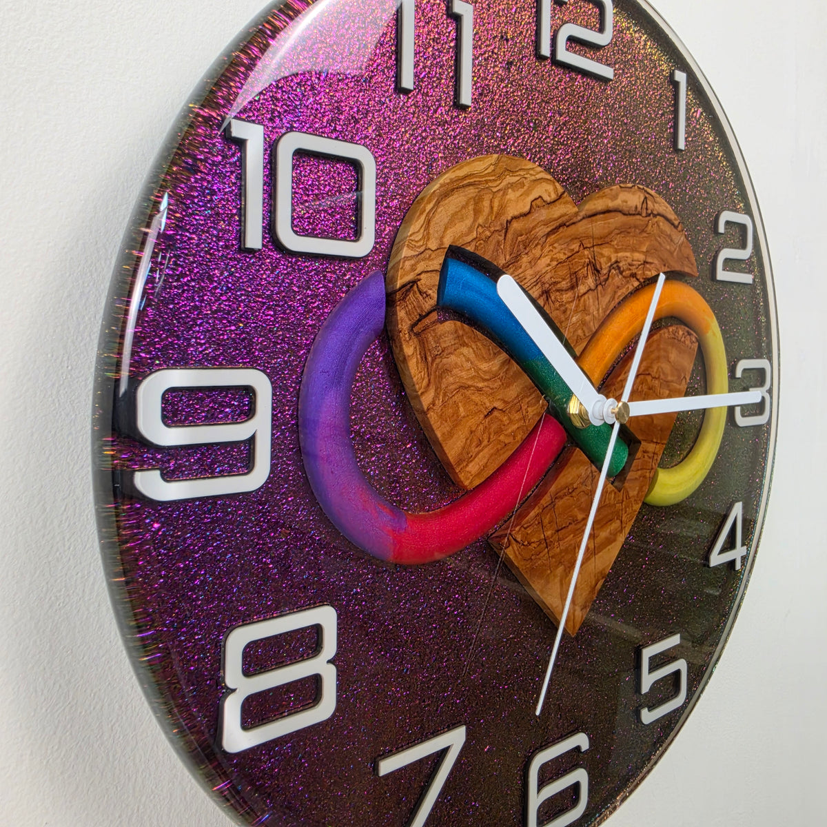 Timeless Symbols Bound Forever wall clock featuring a natural olive wood heart and multicolor infinity design in clear resin.