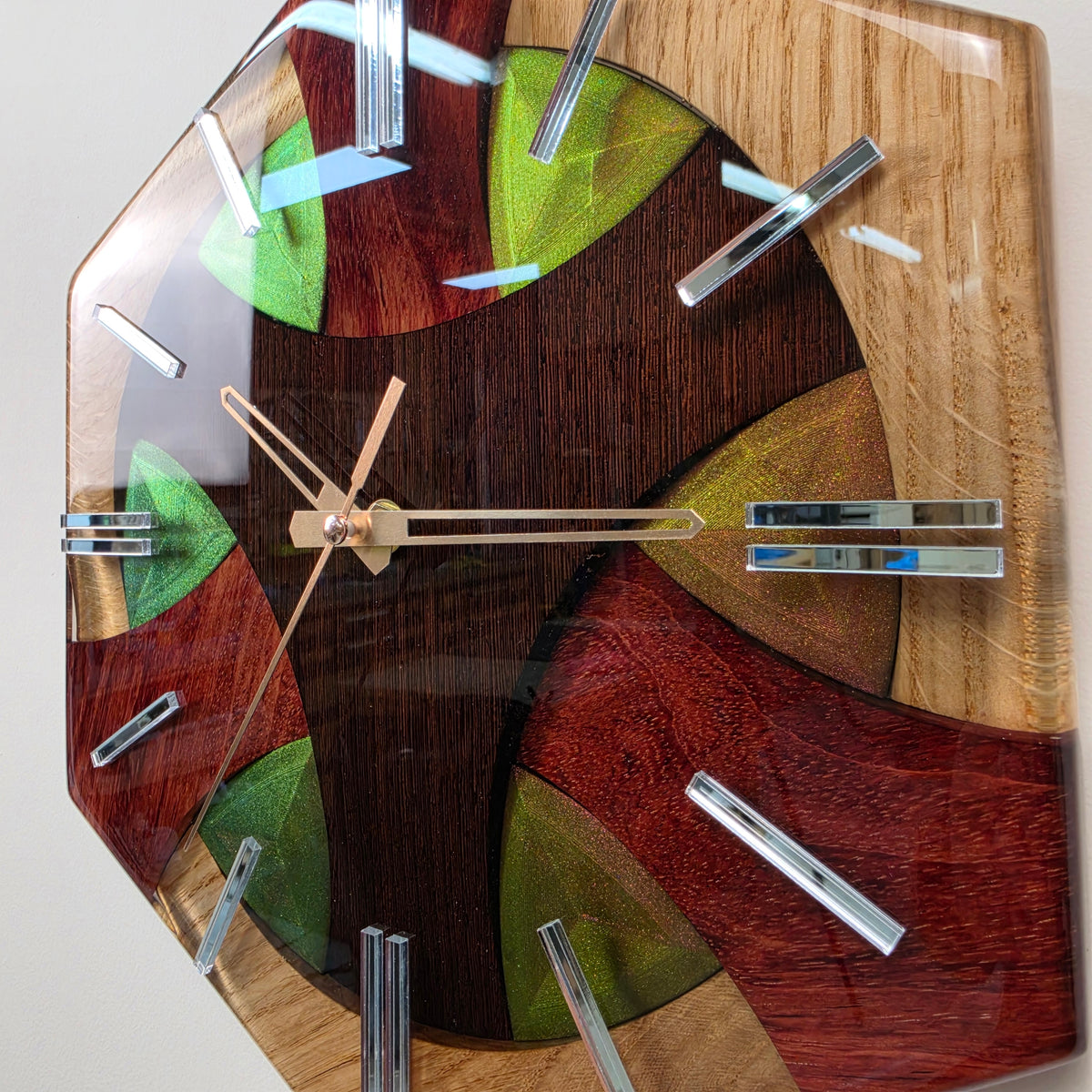 One-of-a-kind wooden wall clock with natural wood grain, colorful resin details and reflective mirrored hour markers.