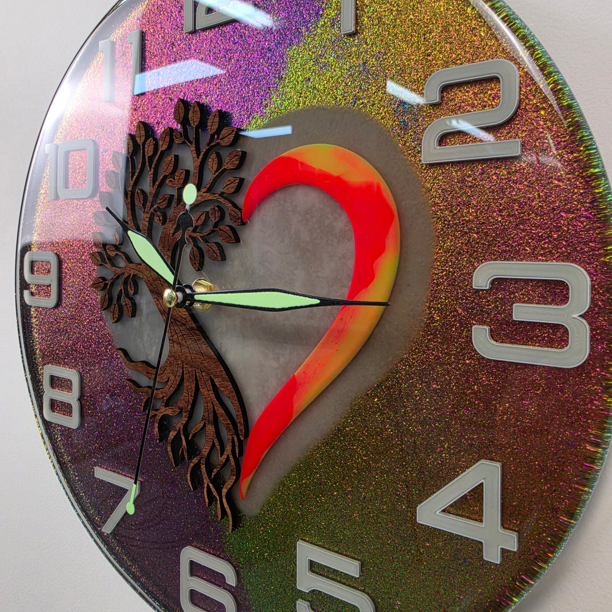 Roots of Life wall clock glowing in the dark with blue heart illumination and green fluorescent numerals.