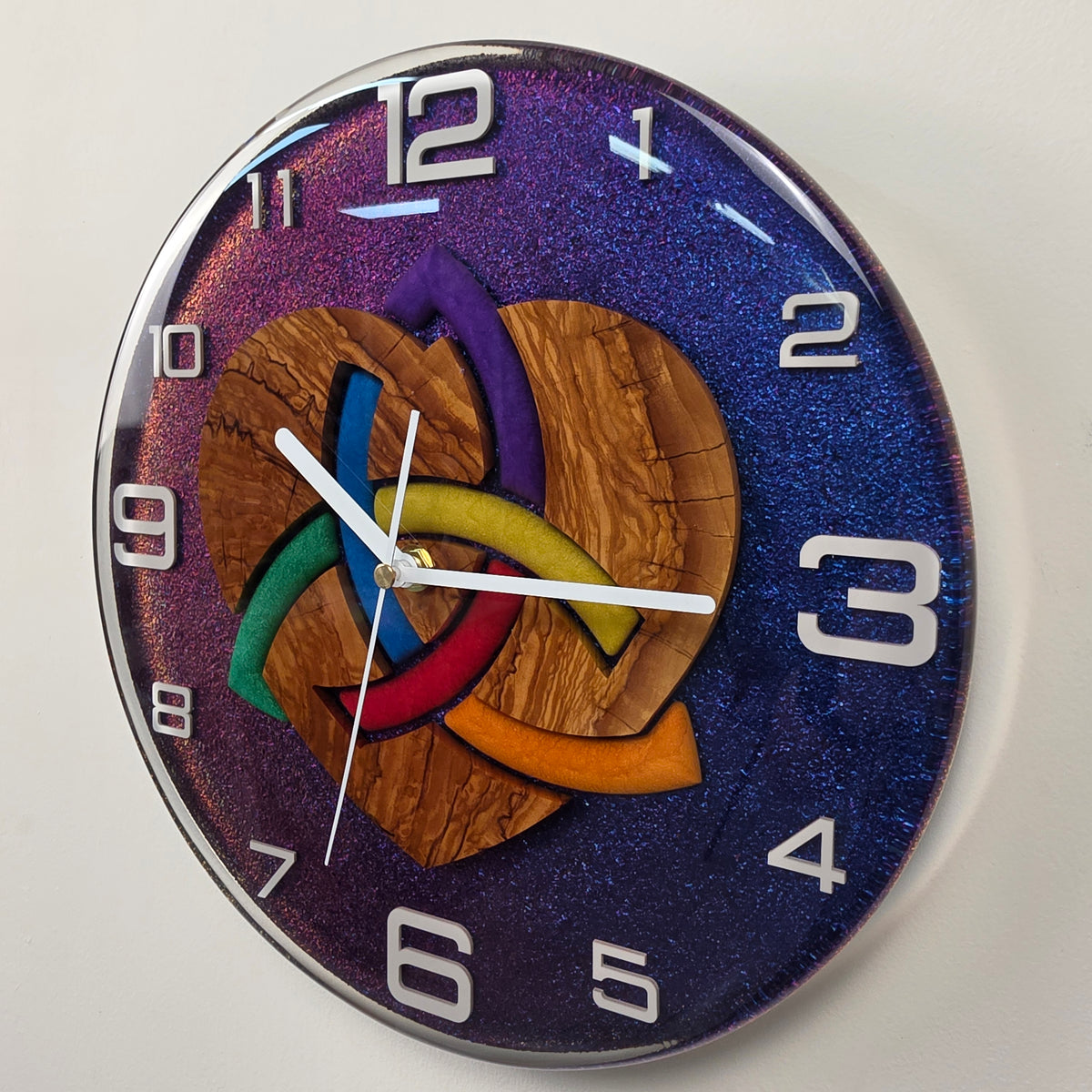 Woven Heart artistic wall clock combining natural olive wood, vibrant colors and a shimmering chameleon background.